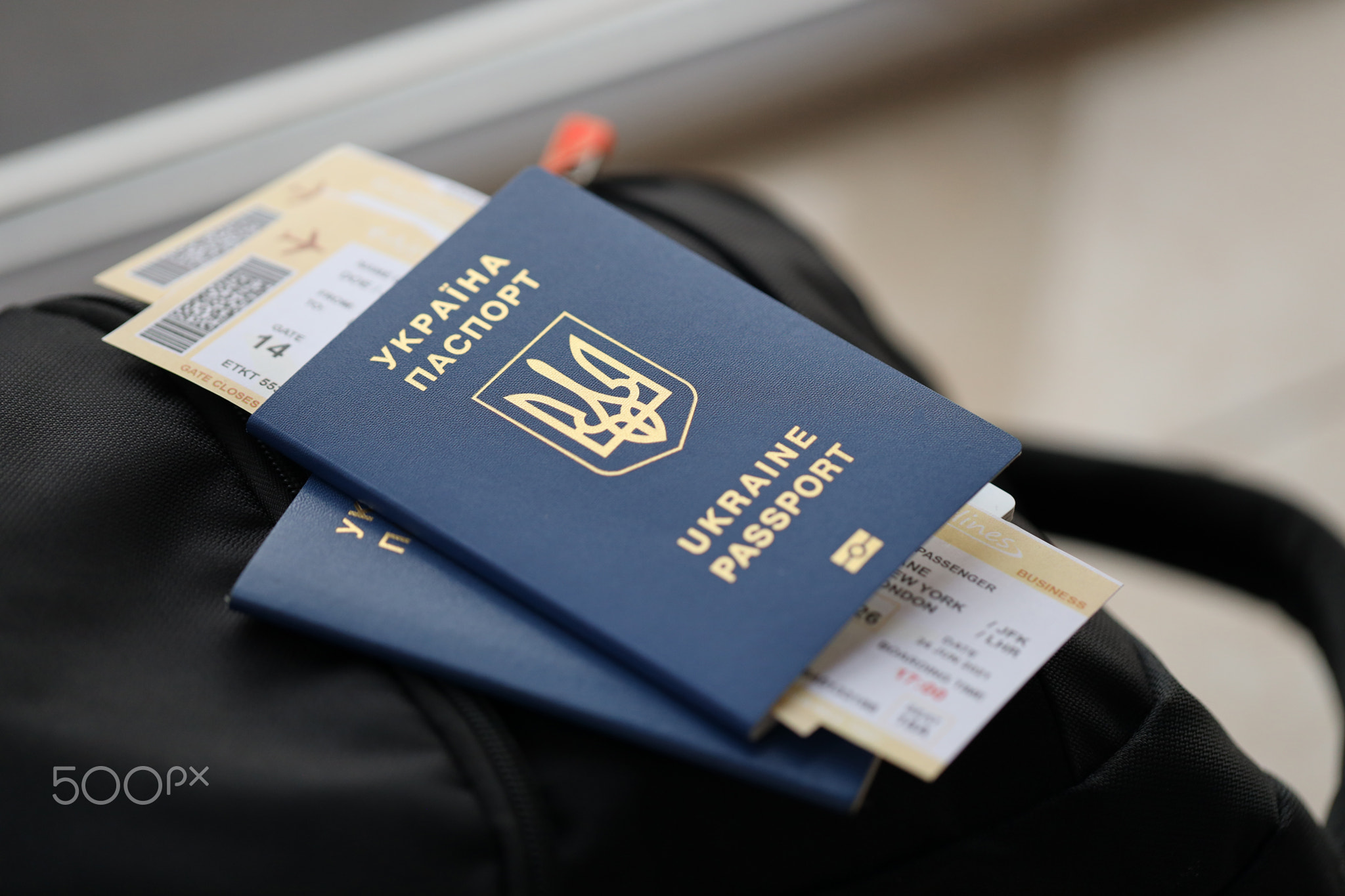Two ukrainian biometrical passports with air flight tickets on black touristic backpack