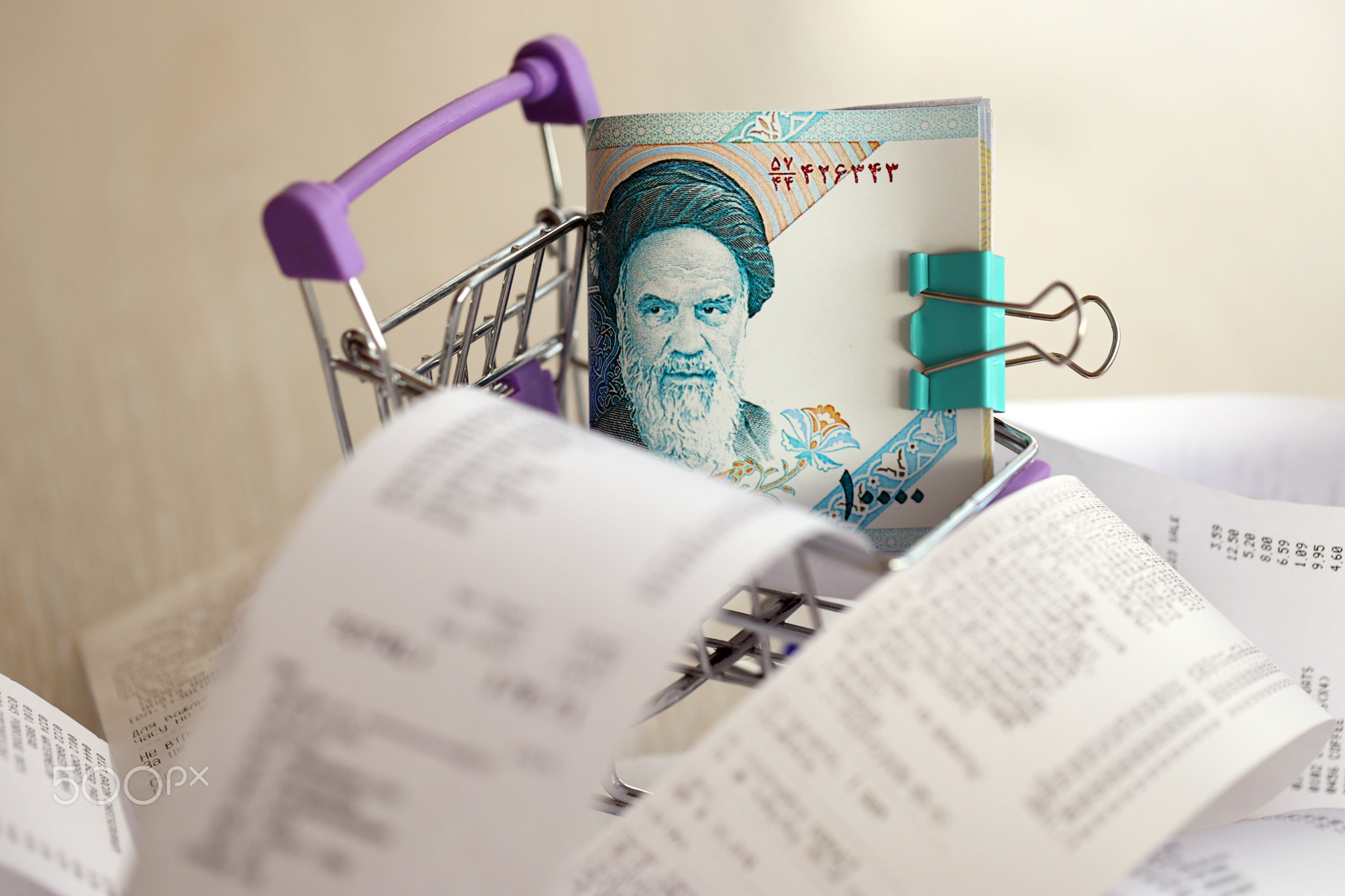 Iranian rials money bills bunch in shopping trolley surrounded by many paper receipts