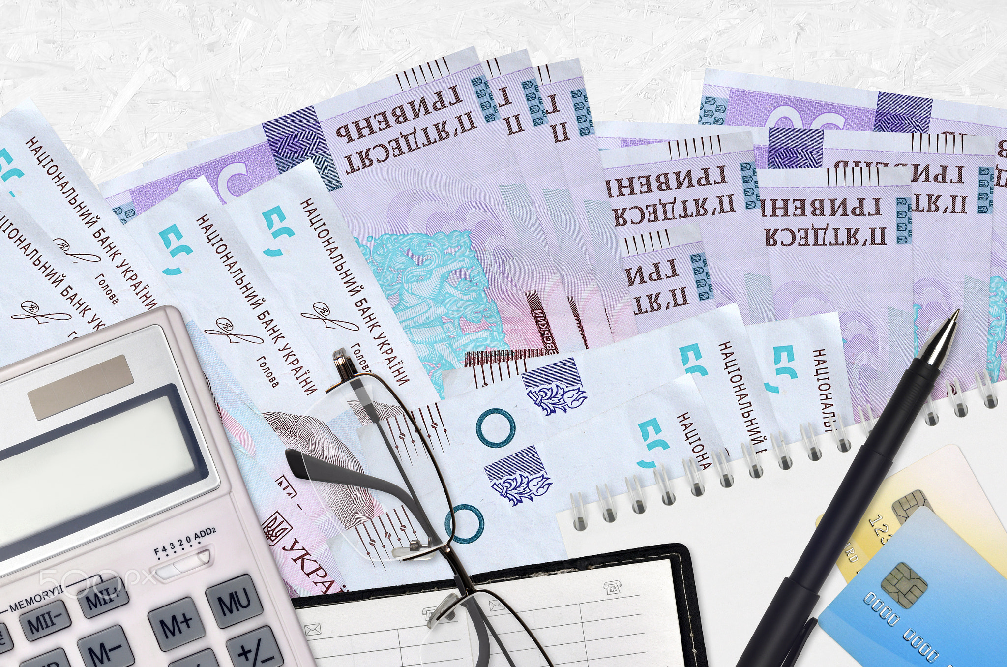 50 Ukrainian hryvnias bills and calculator with glasses and pen. Tax payment concept or investment
