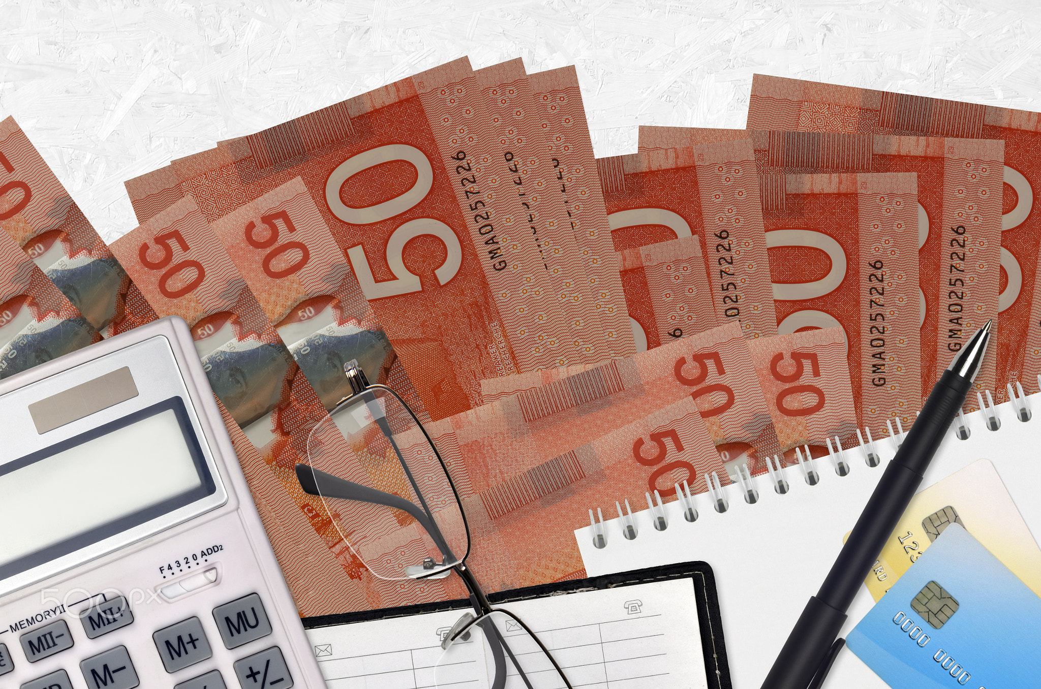 50 Canadian dollars bills and calculator with glasses and pen. Tax payment concept or investment