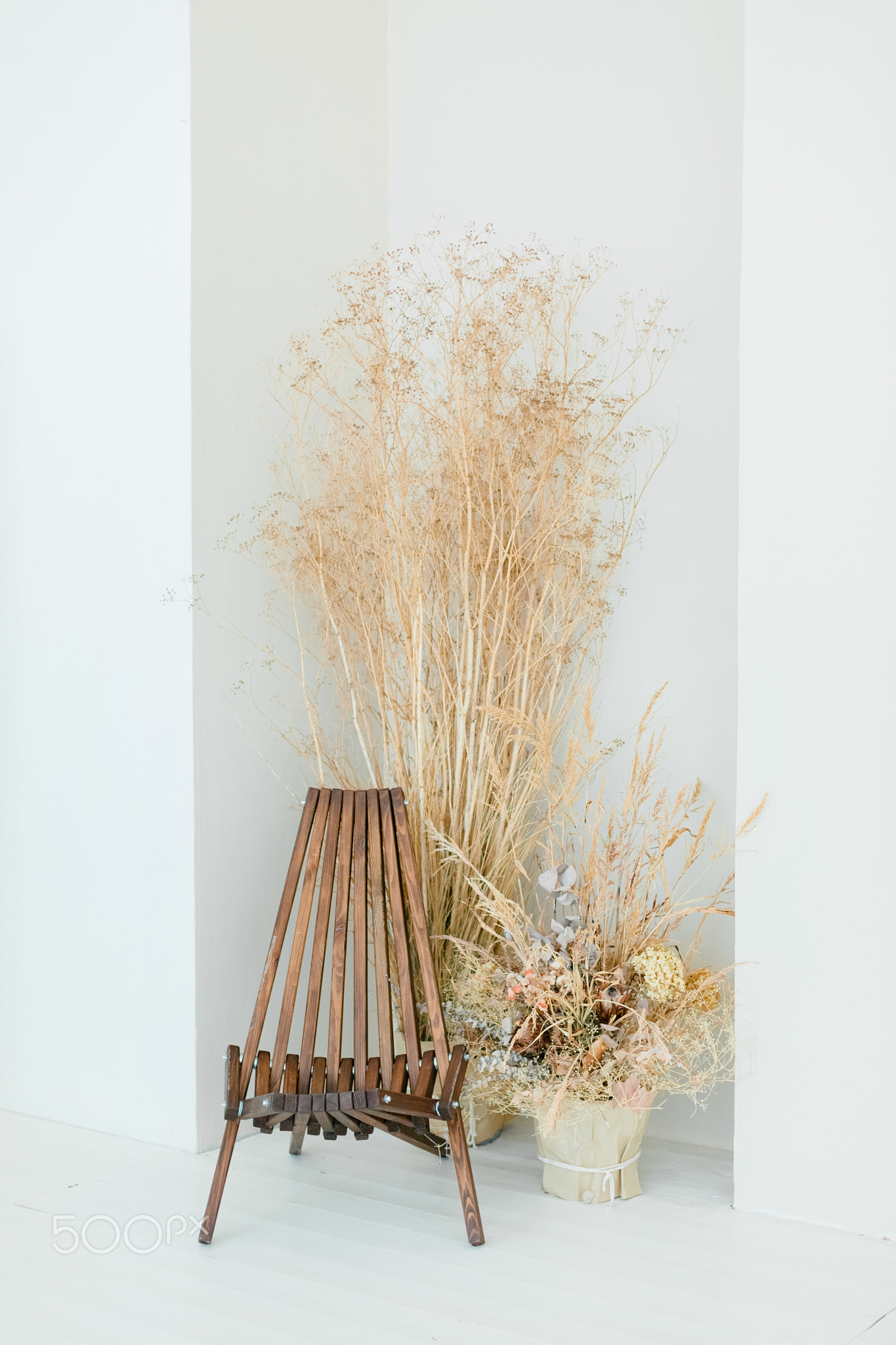 Neutral concept of living room interior with design wooden chair, dried flowers in vase, decoration