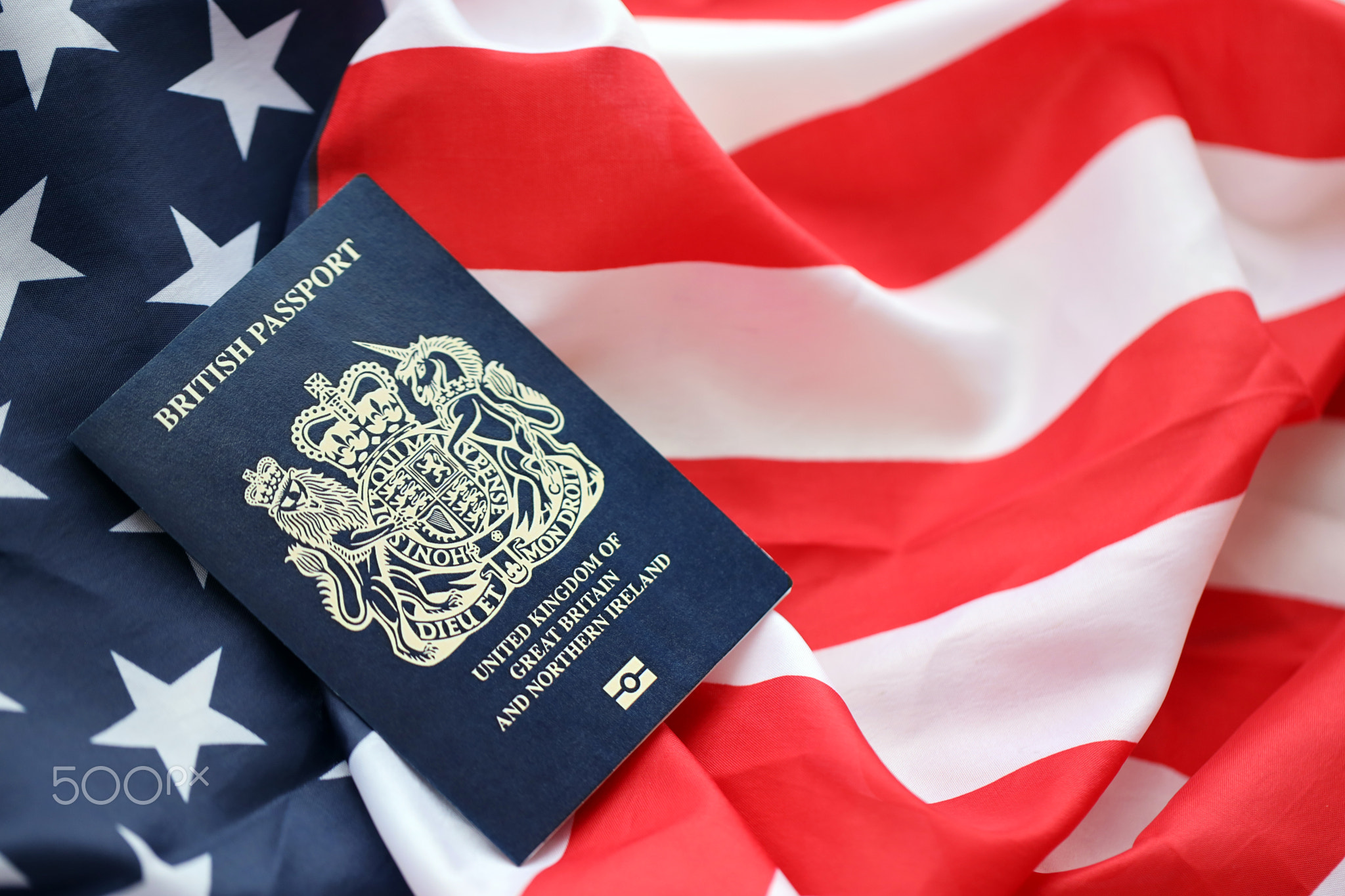 Blue British passport on United States national flag background close up