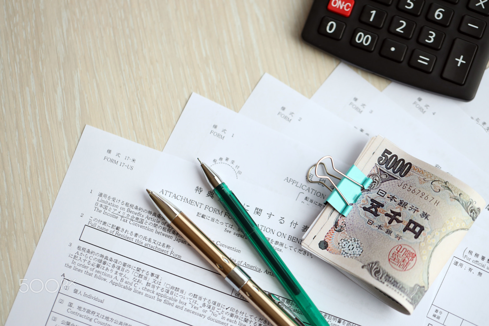 Japanese tax forms lies on table with calculator, pen and japanese yen money bills roll