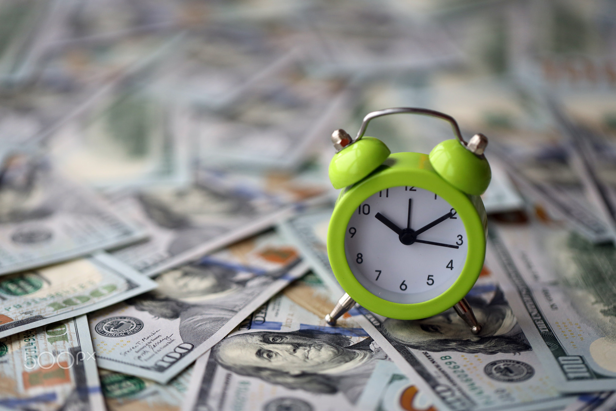 Alarm clock on hundred dollar bills banknotes. Background of time management, business