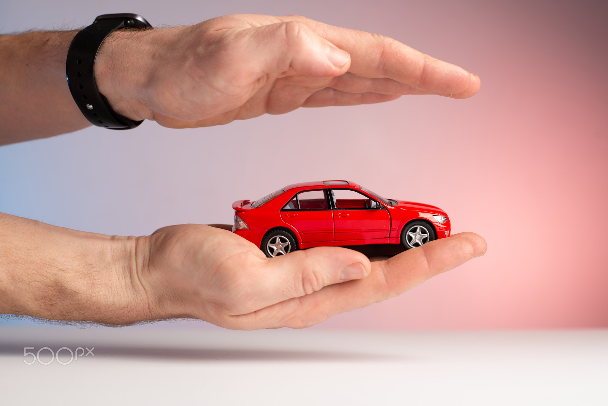 Car insurance. Red toy car on hand. Protect car
