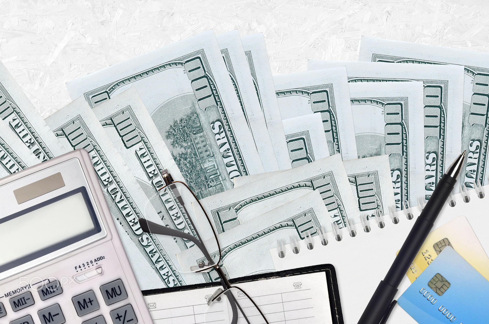100 US dollars bills and calculator with glasses and pen. Tax payment concept or investment