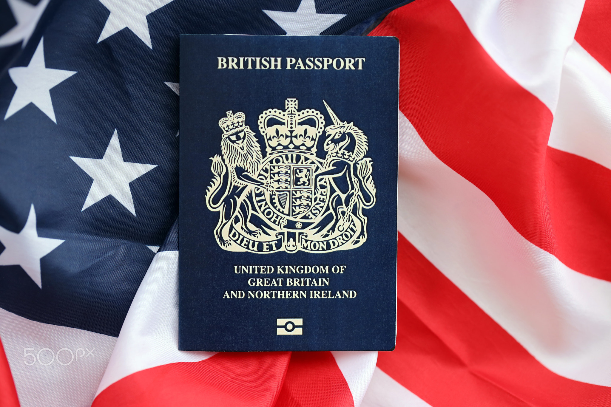 Blue British passport on United States national flag background close up