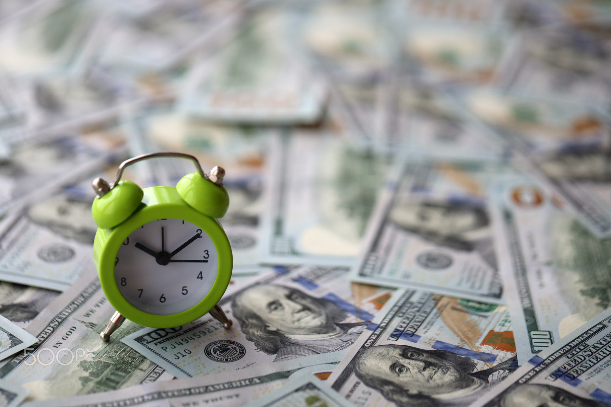 Alarm clock on hundred dollar bills banknotes. Background of time management, business