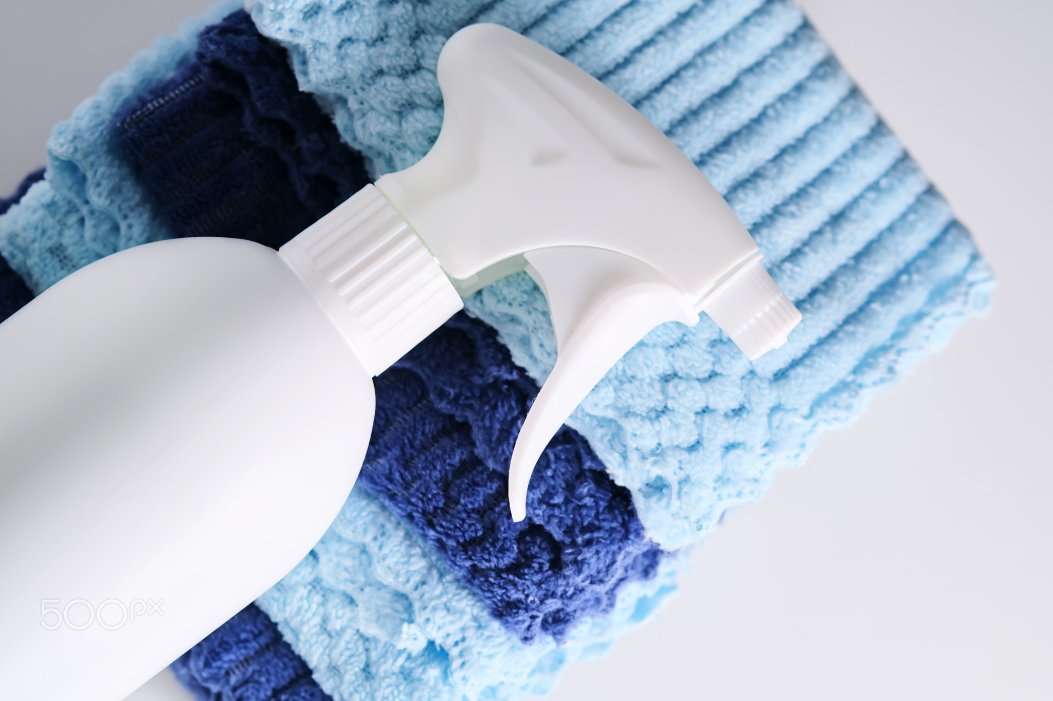 Cleaning product with a sprayer on a background of a blue microfiber cloth.
