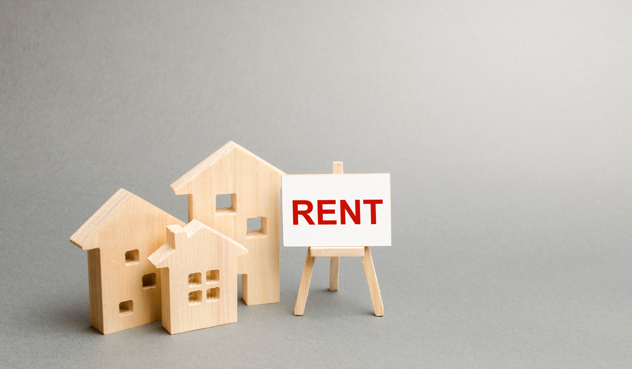 Three figures of houses and an easel with the word rent. The concept of temporary rental housing and