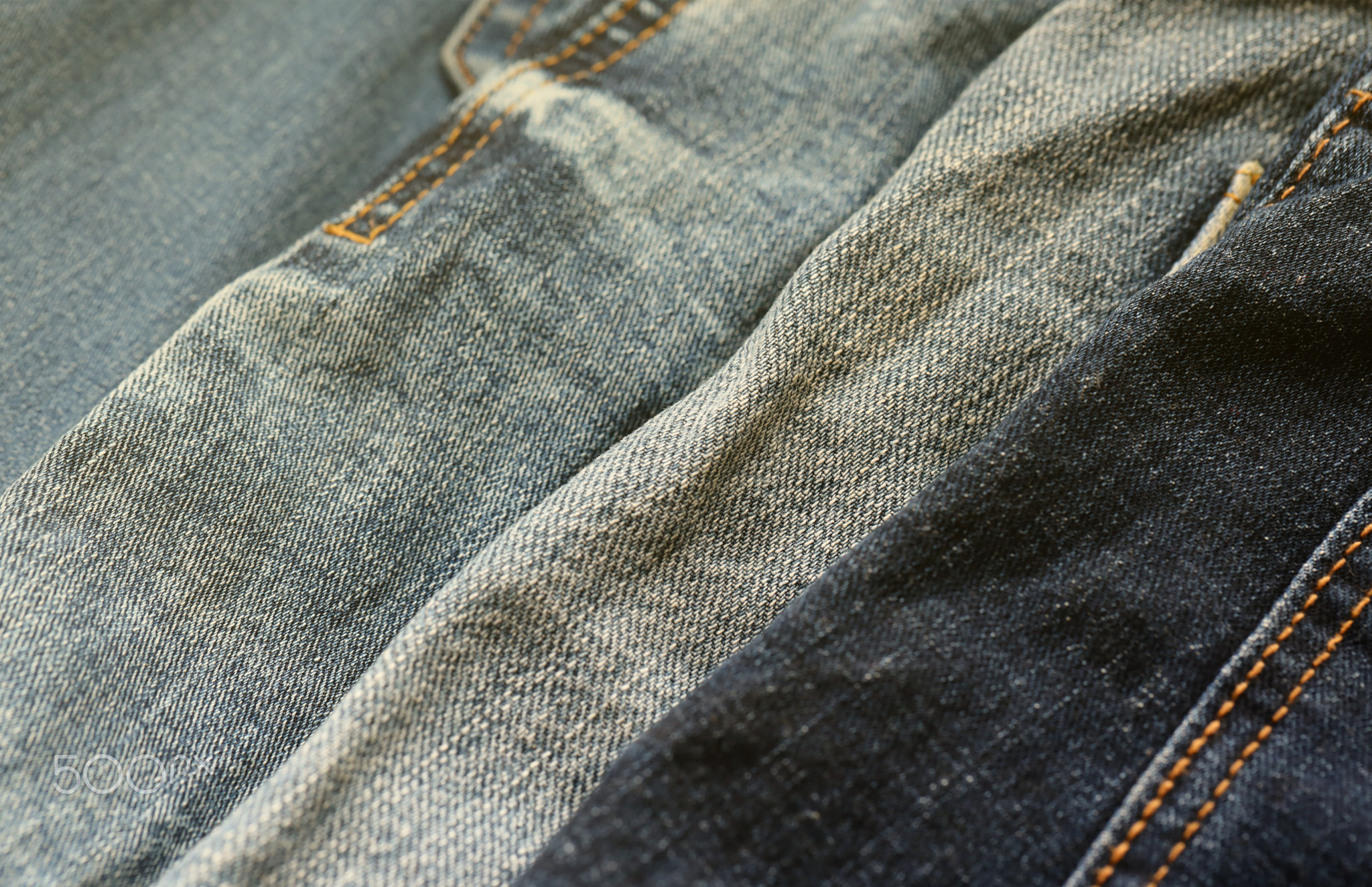 Many jeans in stack in wardrobe room. Row of pants denim jeans in closet. Concept of buy, sell