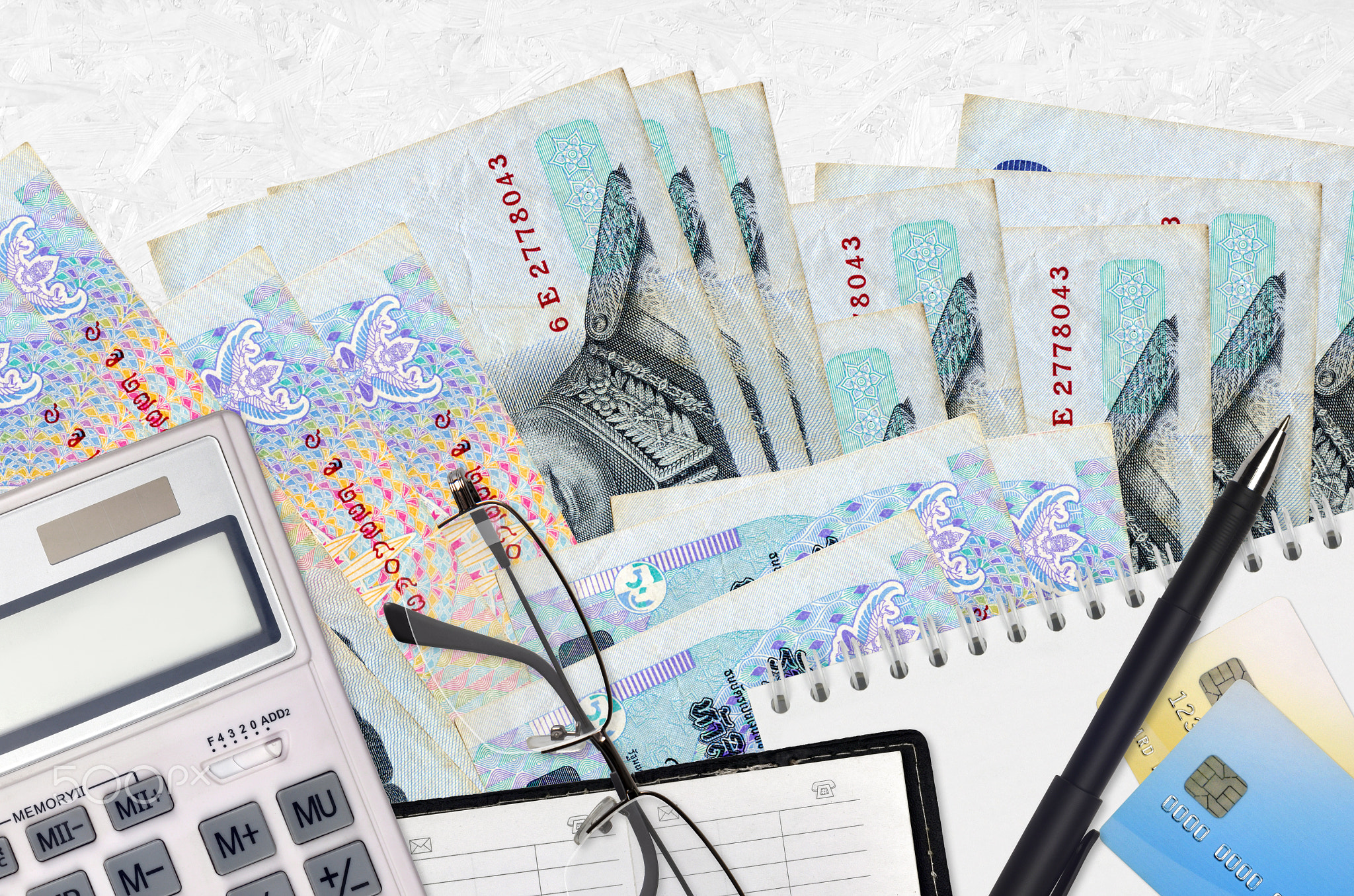 50 Thai Baht bills and calculator with glasses and pen. Tax payment concept or investment solutions