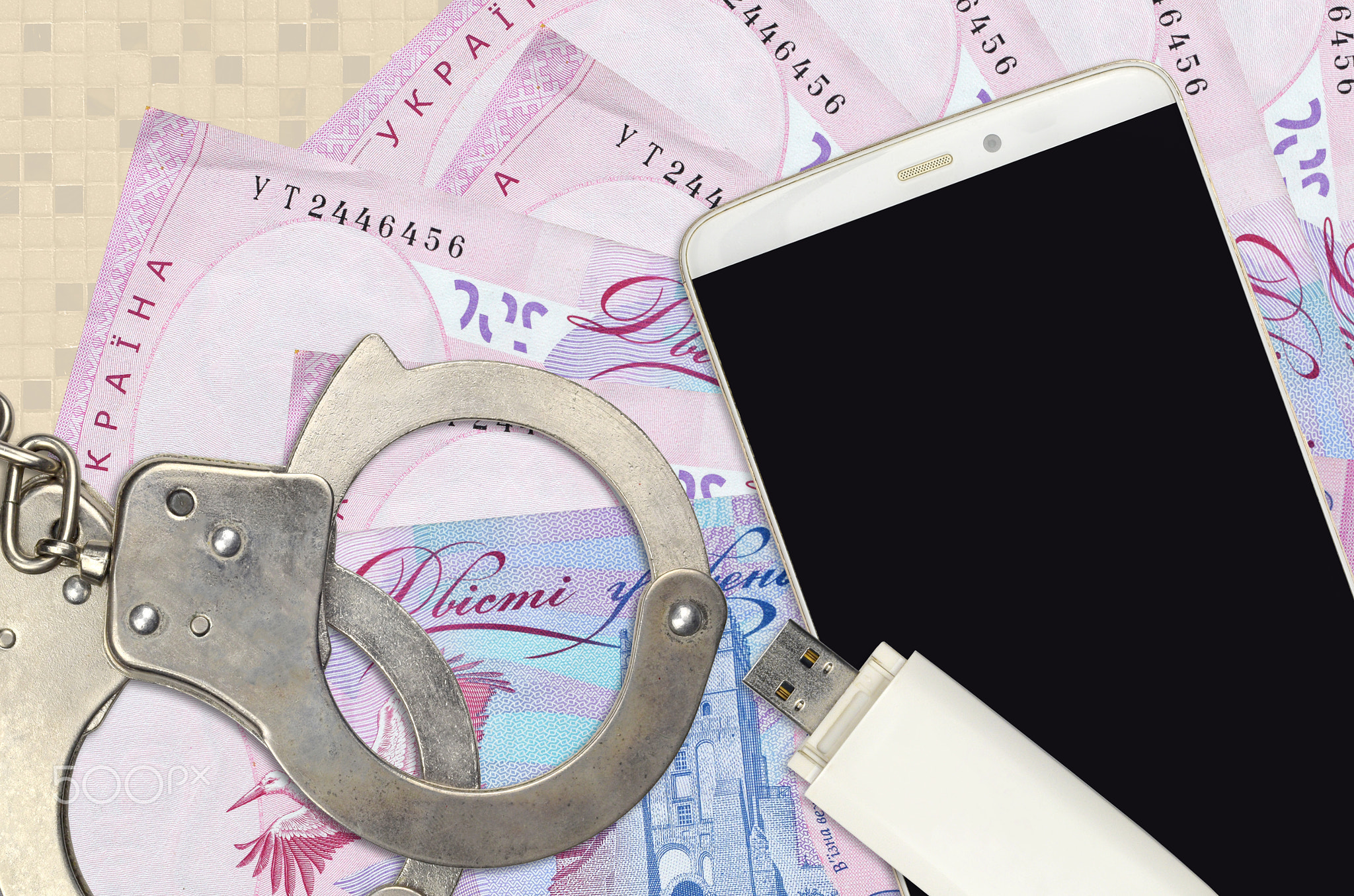 200 Ukrainian hryvnias bills and smartphone with police handcuffs. Concept of hackers phishing