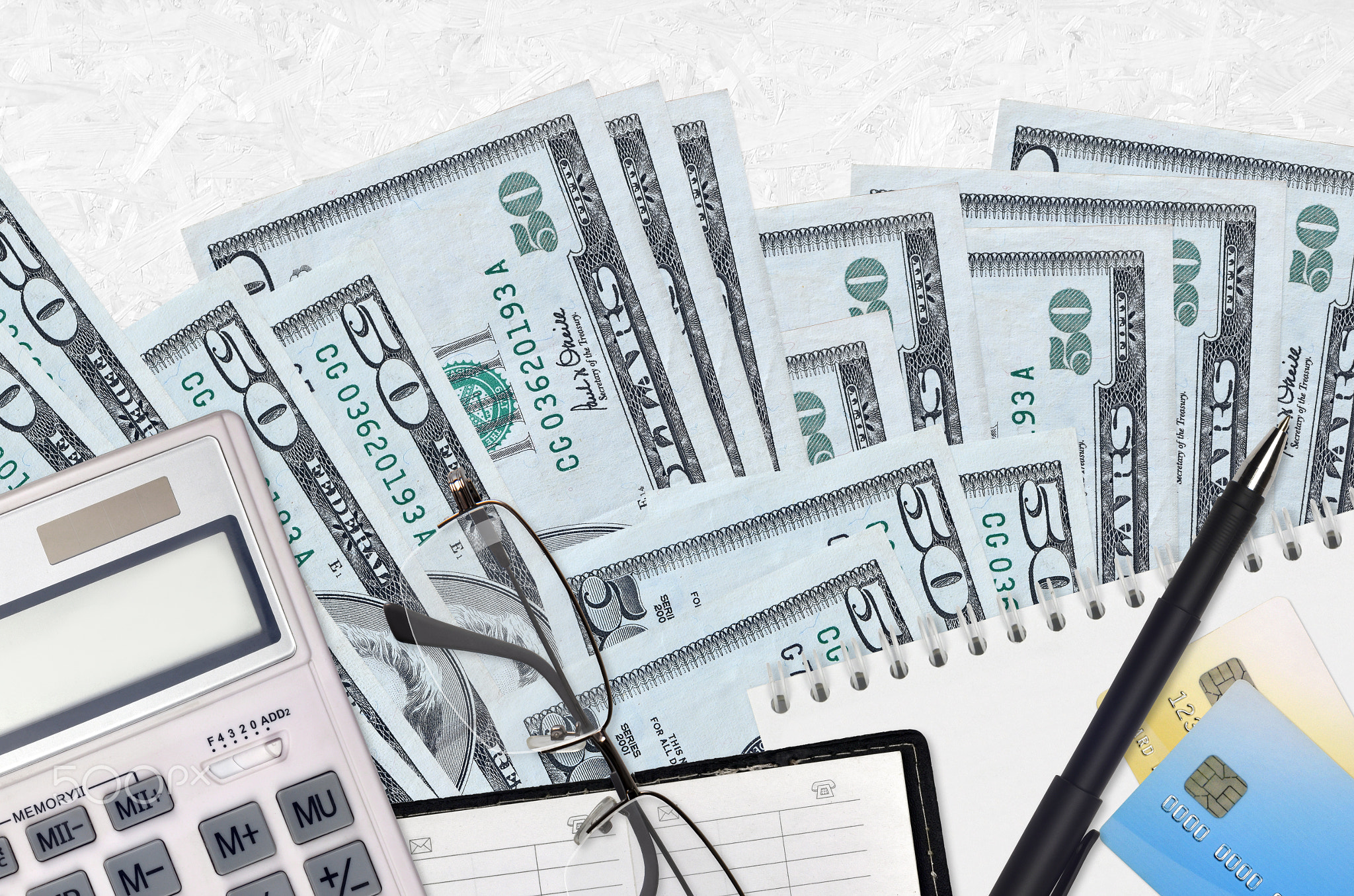 50 US dollars bills and calculator with glasses and pen. Tax payment concept or investment solutions