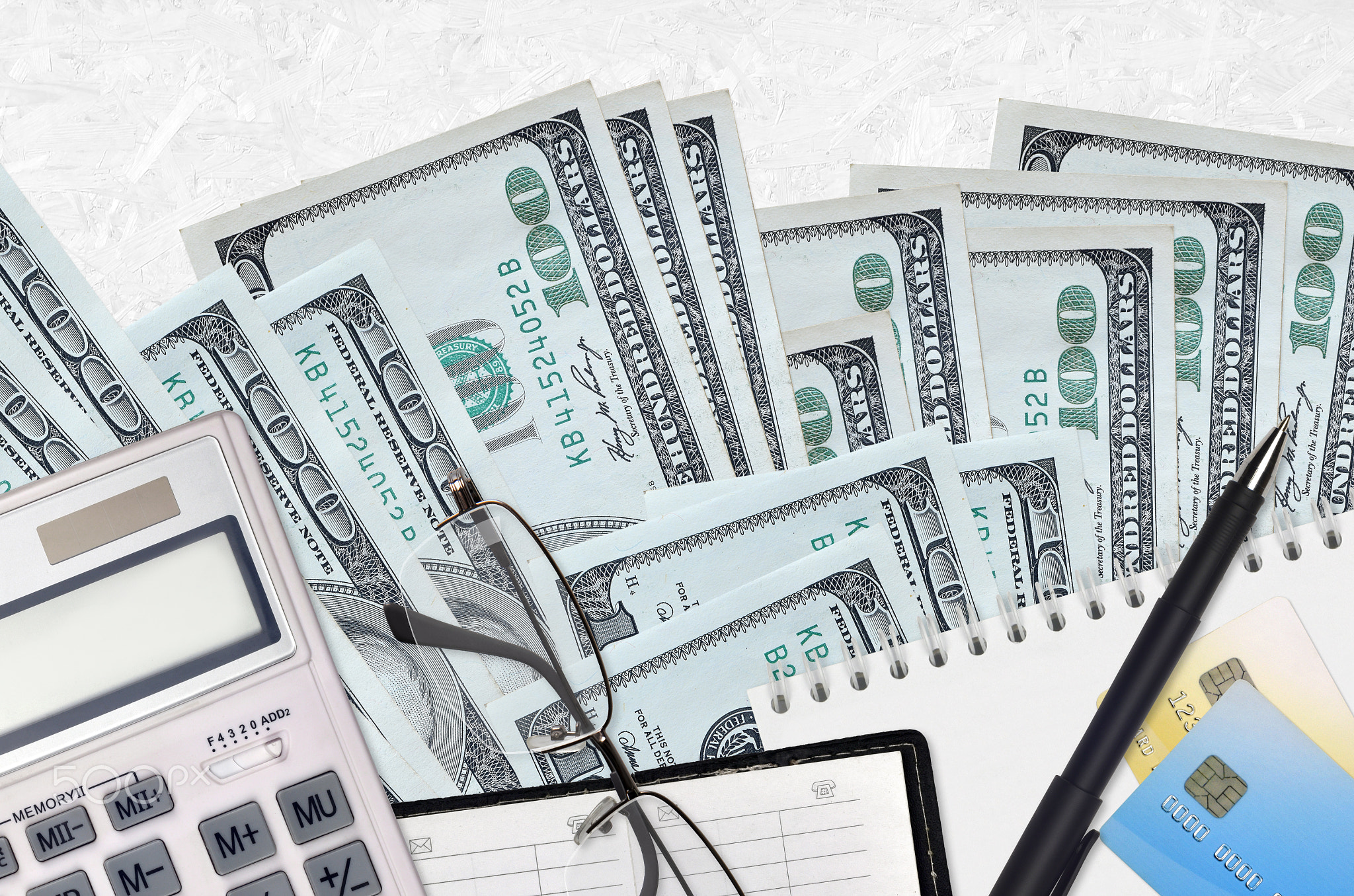 100 US dollars bills and calculator with glasses and pen. Tax payment concept or investment