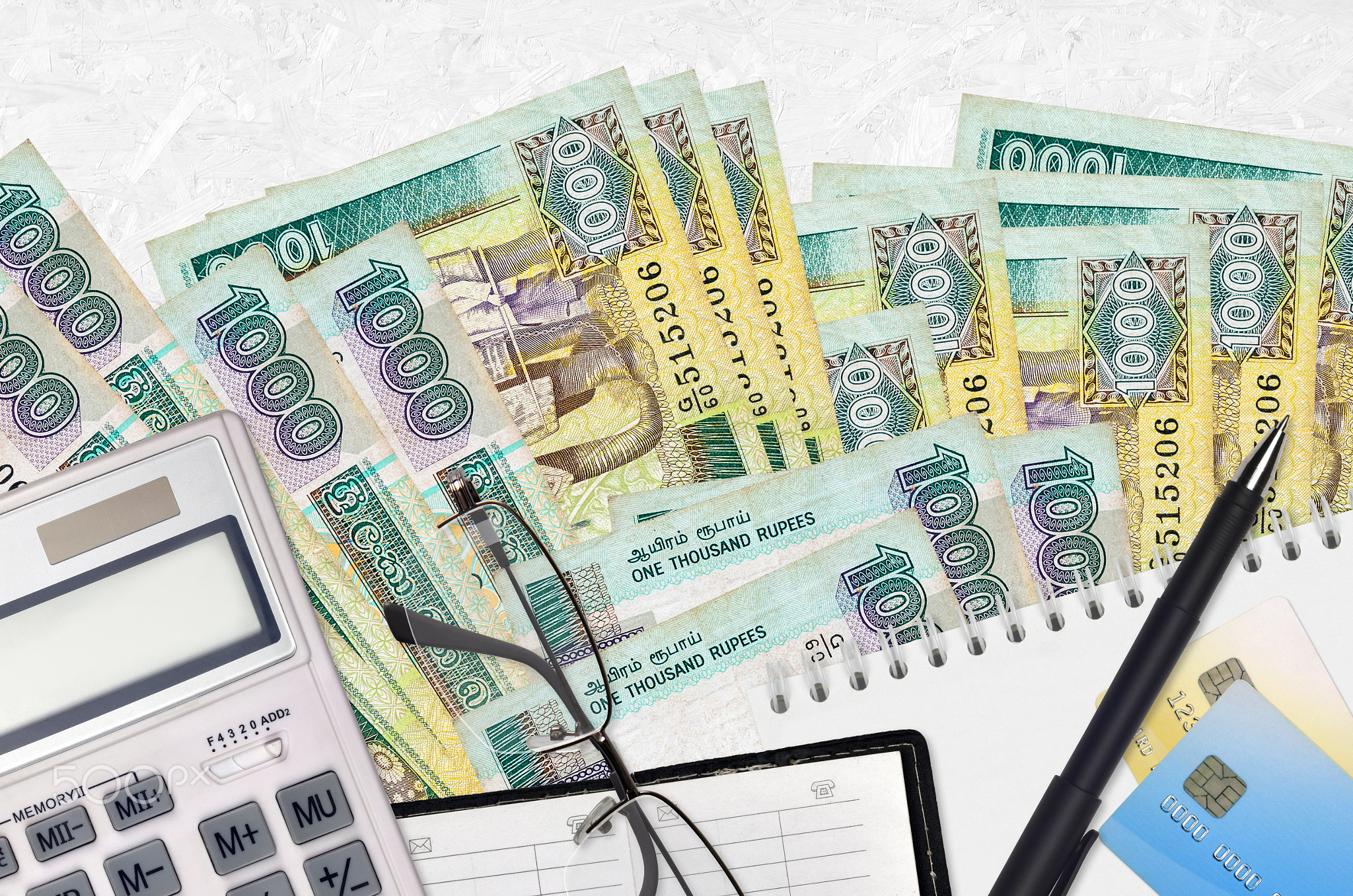 1000 Sri Lankan rupees bills and calculator with glasses and pen. Tax payment concept or investment
