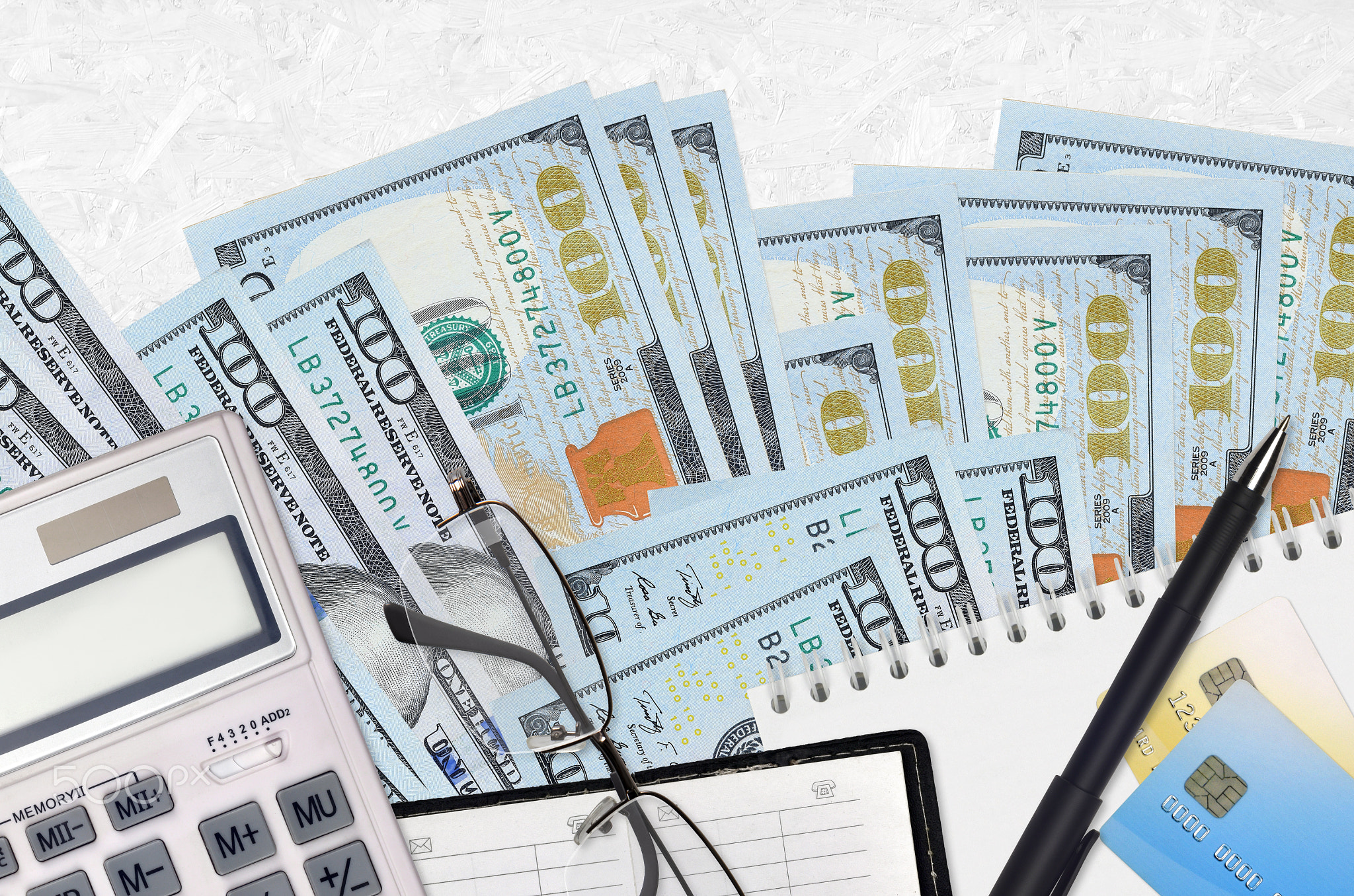 100 US dollars bills and calculator with glasses and pen. Tax payment concept or investment