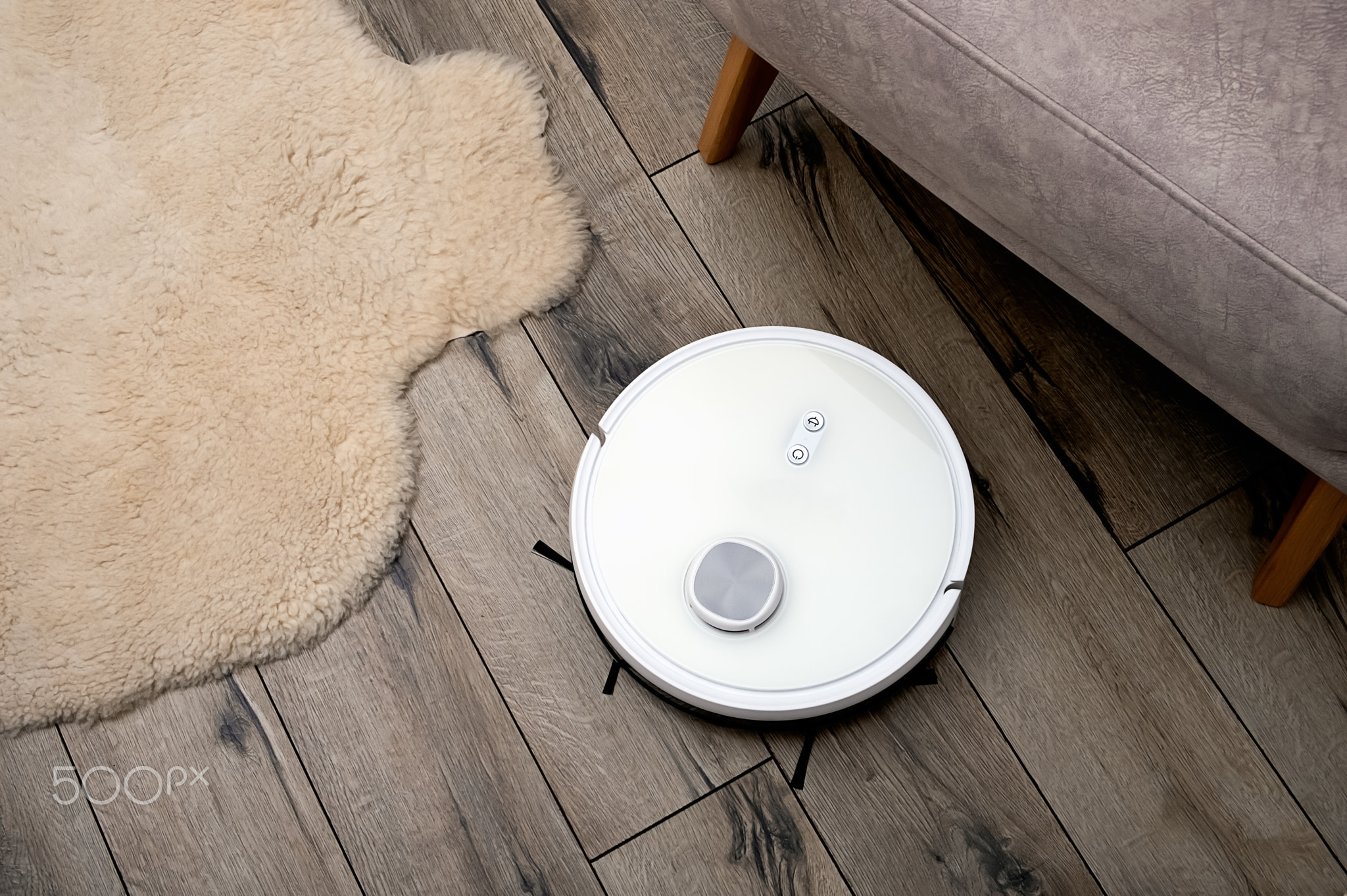 A robot vacuum cleaner on a wooden floor in a modern interior. Selective focus.