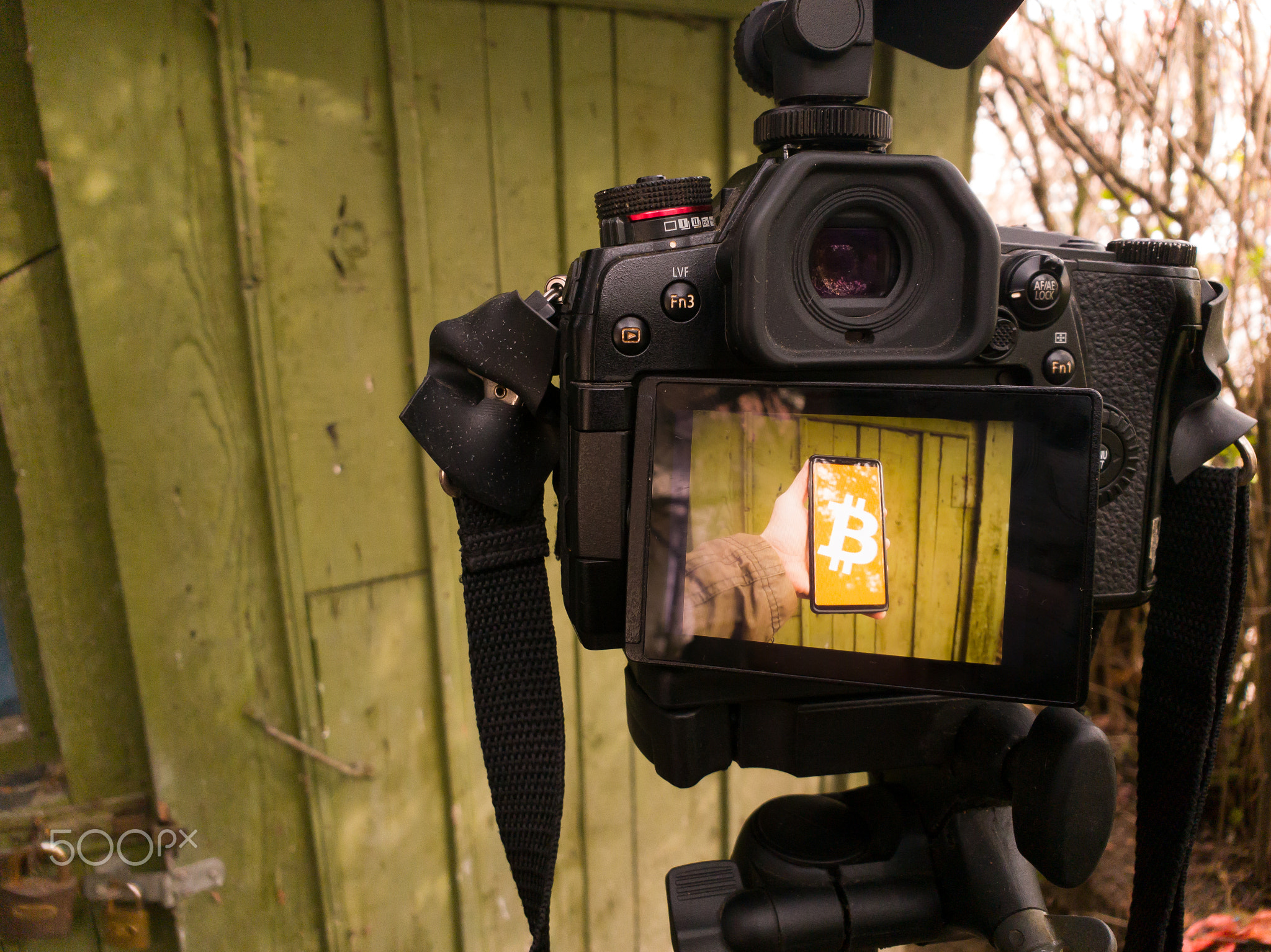 On the display of a digital camera, a hand-held smartphone displaying a bitcoin symbol. BTC concept.