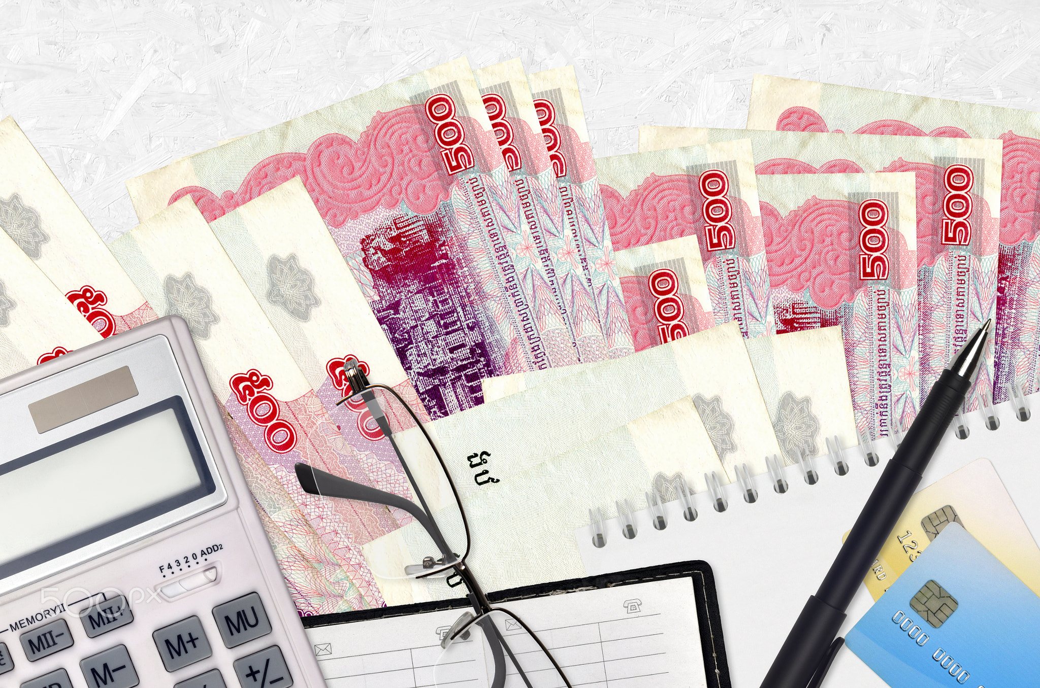 500 Cambodian riels bills and calculator with glasses and pen. Tax payment concept or investment