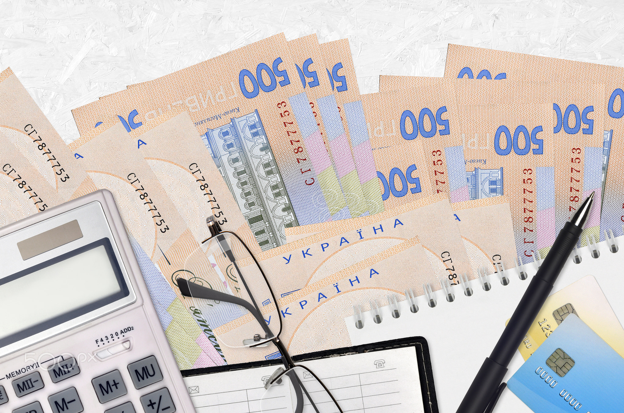 500 Ukrainian hryvnias bills and calculator with glasses and pen. Tax payment concept or investment