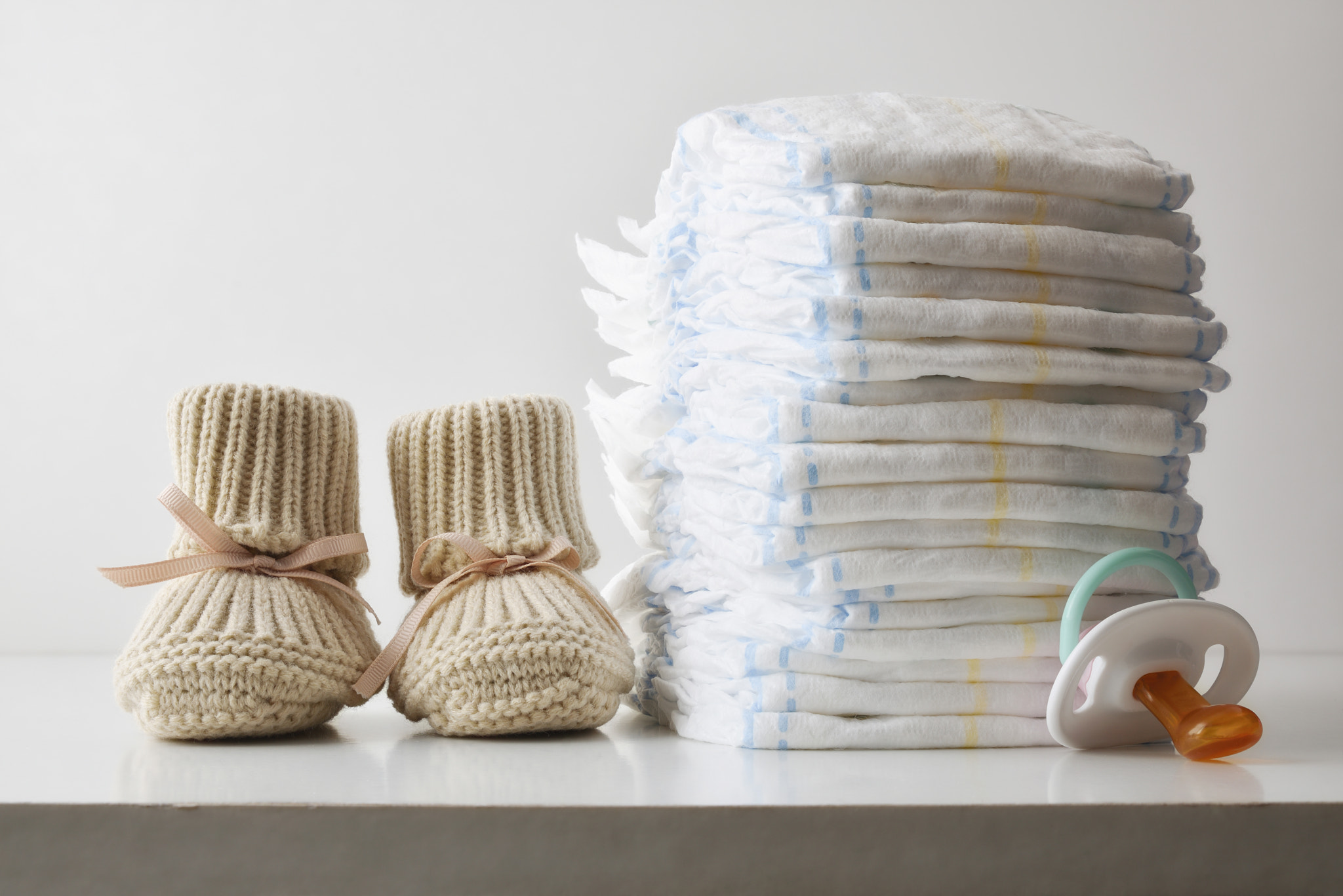 Stack of diaper booties and pacifier isolated on white background