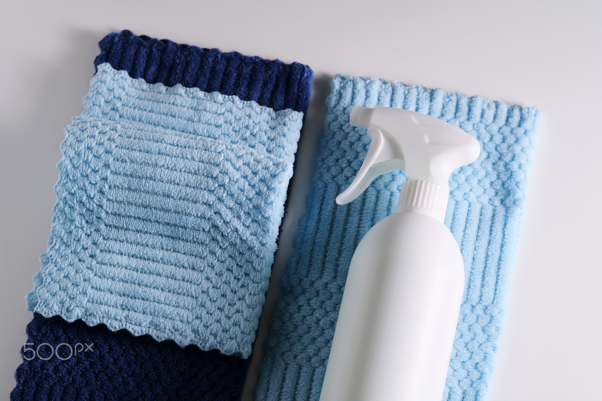 Cleaning product with a sprayer on a background of a blue microfiber cloth.