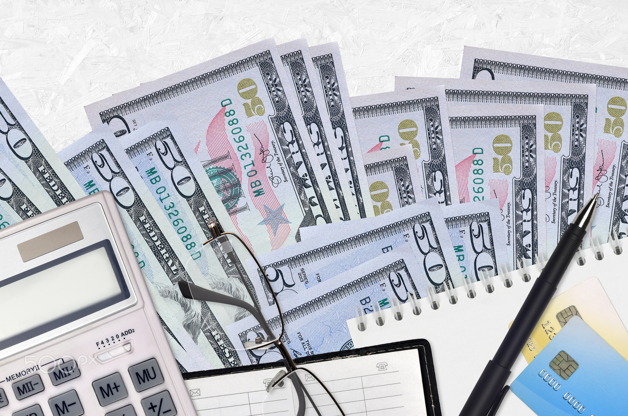 50 US dollars bills and calculator with glasses and pen. Tax payment concept or investment solutions