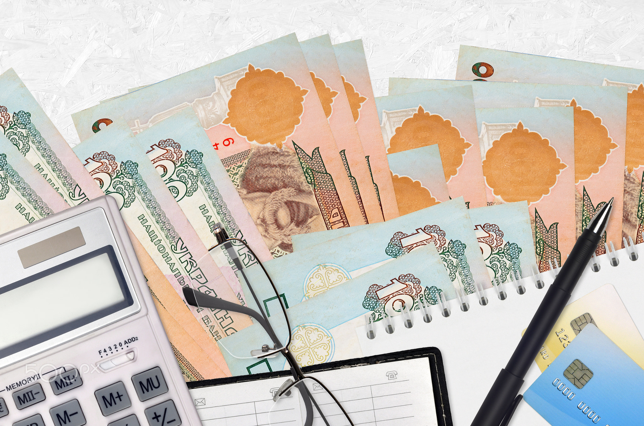 100 Ukrainian hryvnias bills and calculator with glasses and pen. Tax payment concept or investment