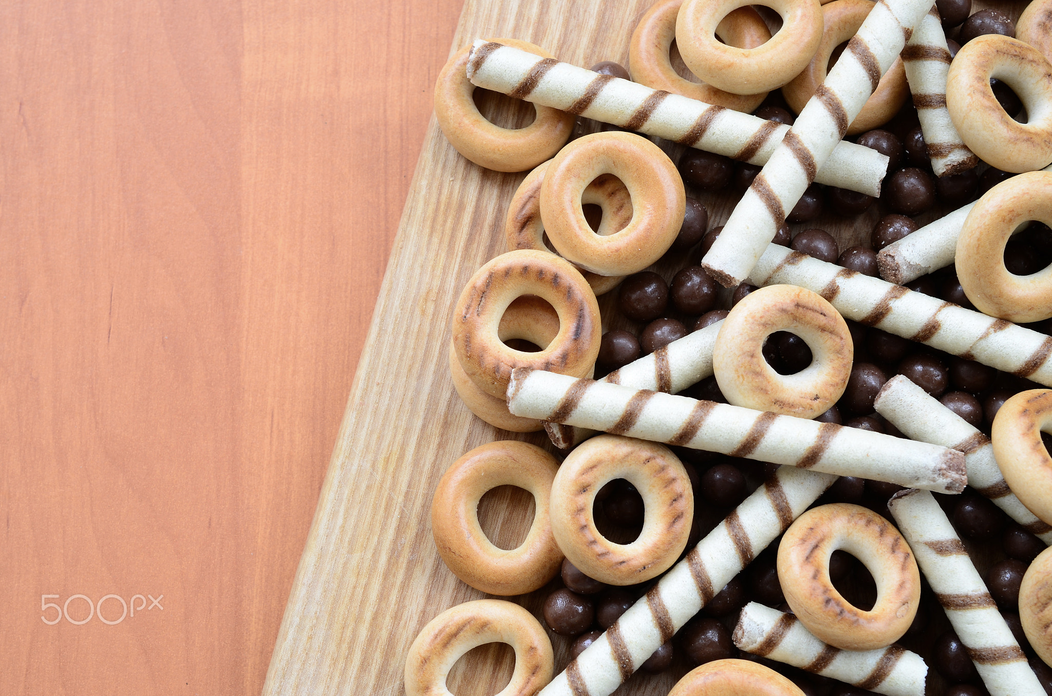 Crispy tubules, chocolate melting balls and bagels lie on a wooden surface. Mix of various sweets