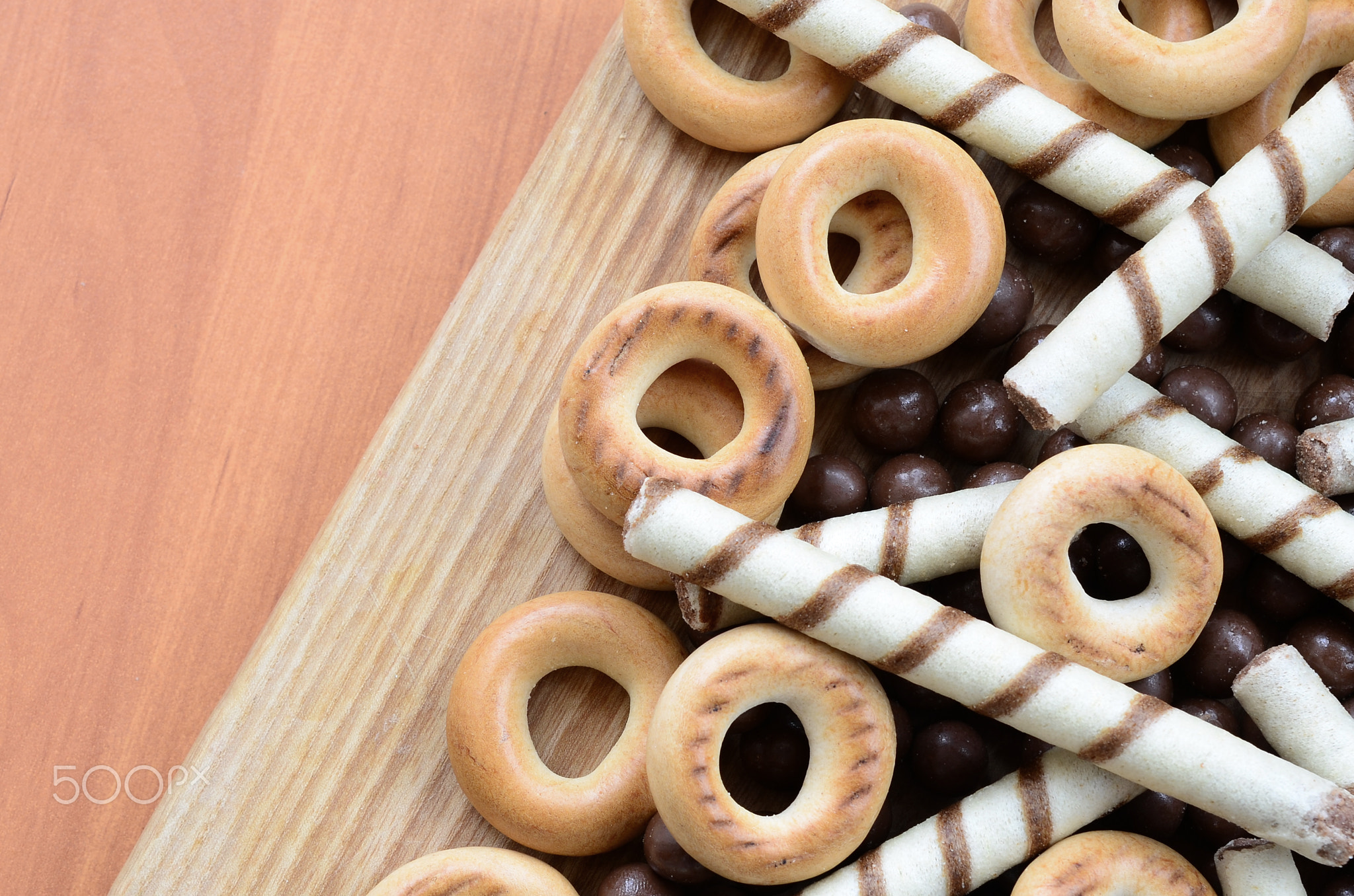 Crispy tubules, chocolate melting balls and bagels lie on a wooden surface. Mix of various sweets