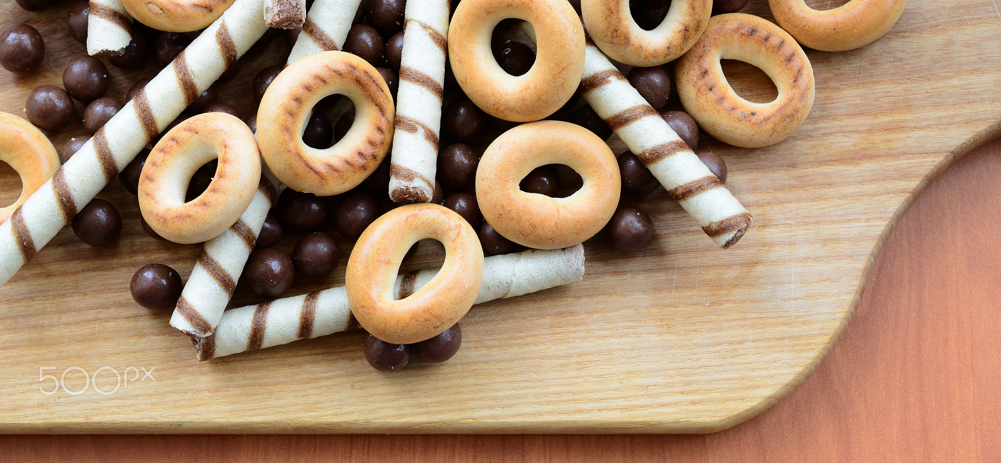 Crispy tubules, chocolate melting balls and bagels lie on a wooden surface. Mix of various sweets