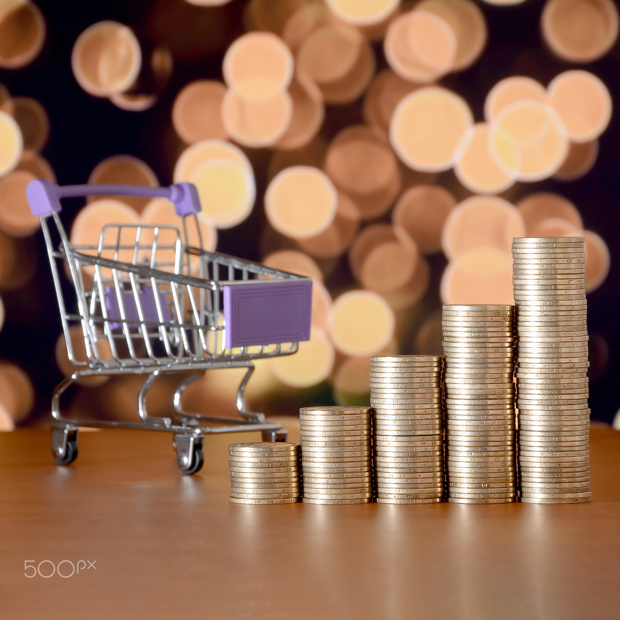 Empty shopping cart and money stacks in growth graph on background of colored bokeh christmas lights