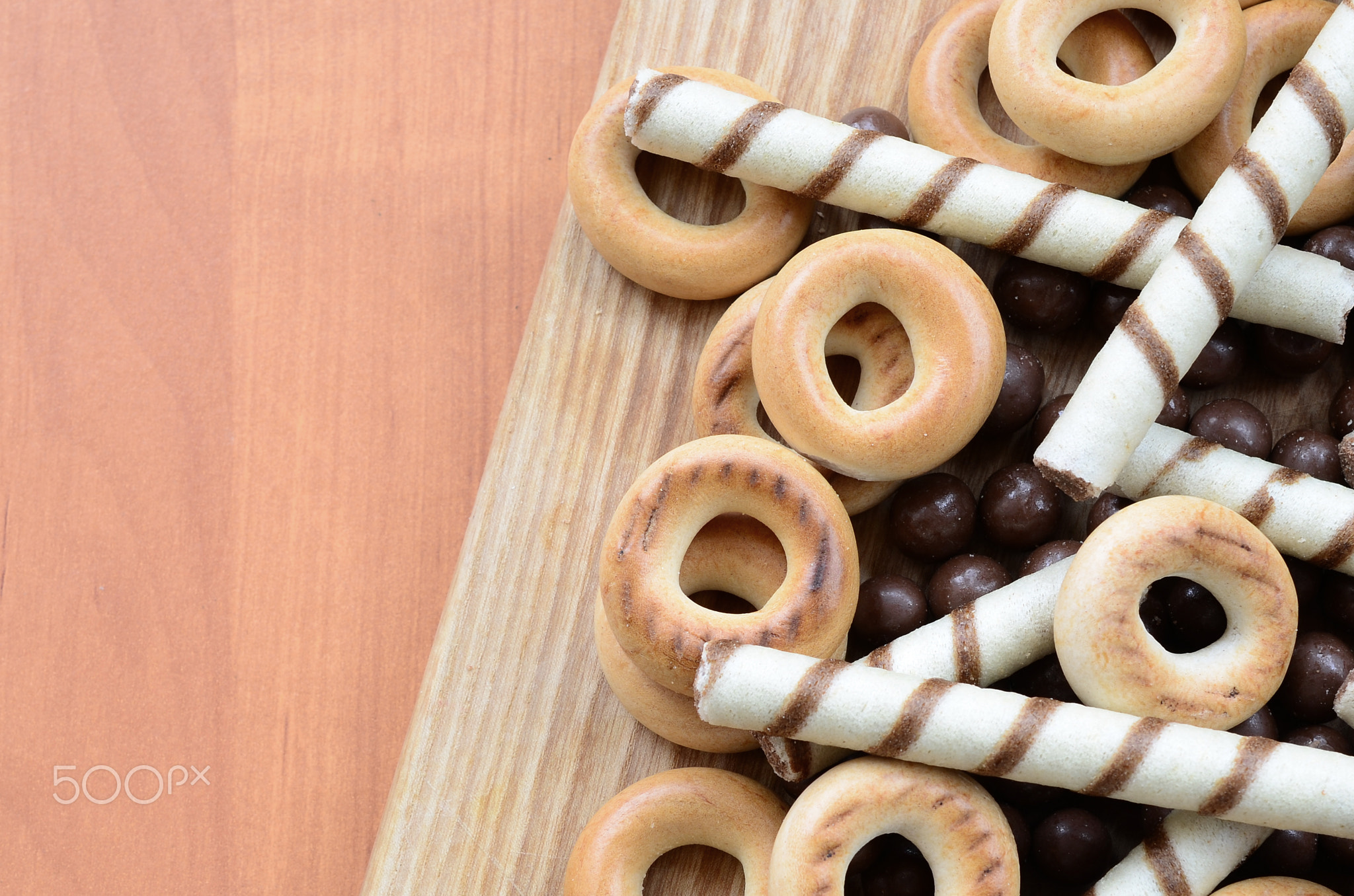 Crispy tubules, chocolate melting balls and bagels lie on a wooden surface. Mix of various sweets