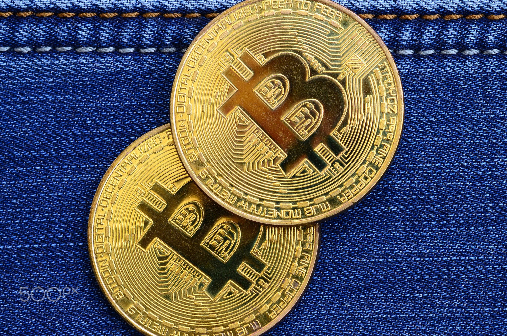 Two golden Bitcoins is lies on a blue jeans fabric. New virtual money. New crypto currency in the