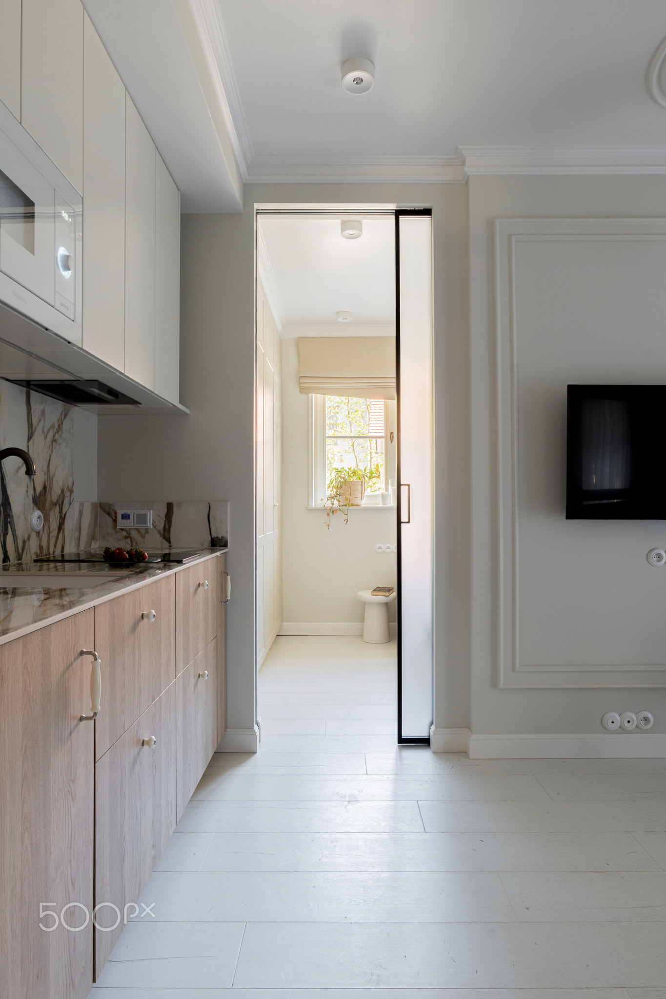 a kitchen with a sliding glass door leading to a living room