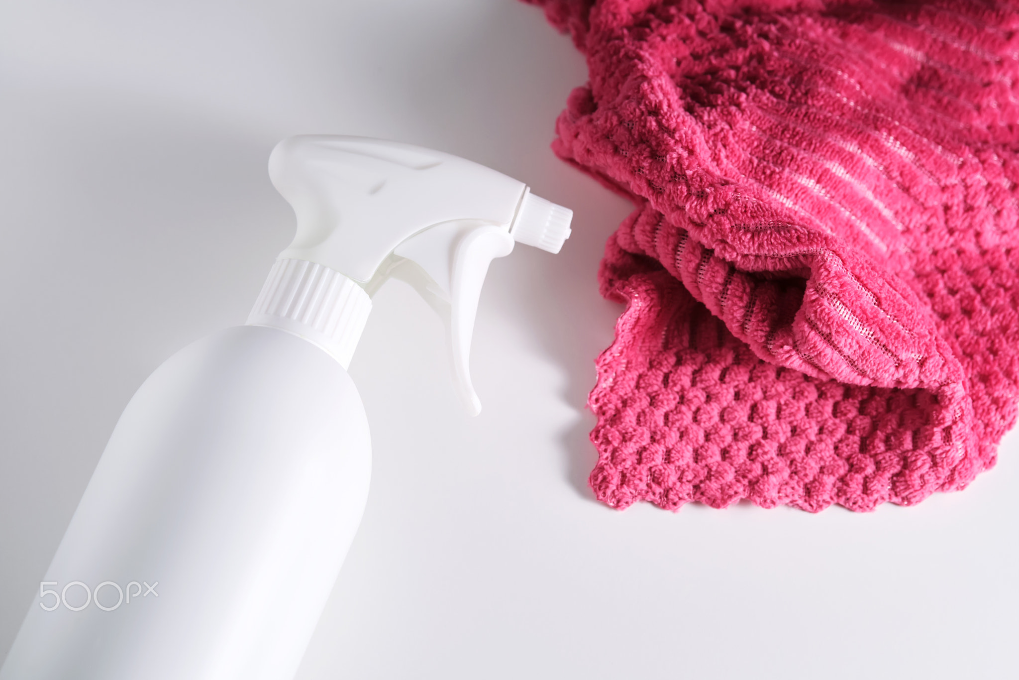 Cleaning product with a sprayer on a background of a red microfiber cloth.