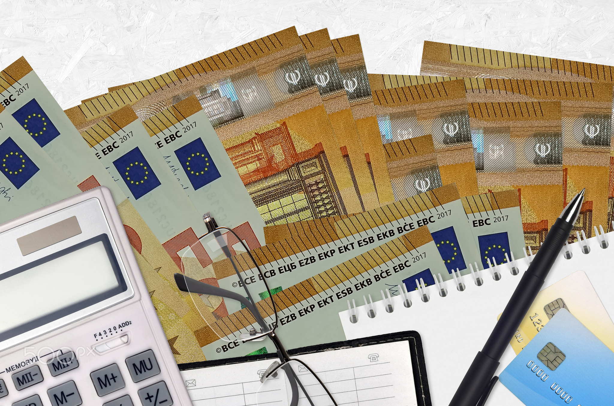 50 euro bills and calculator with glasses and pen. Tax payment concept or investment solutions