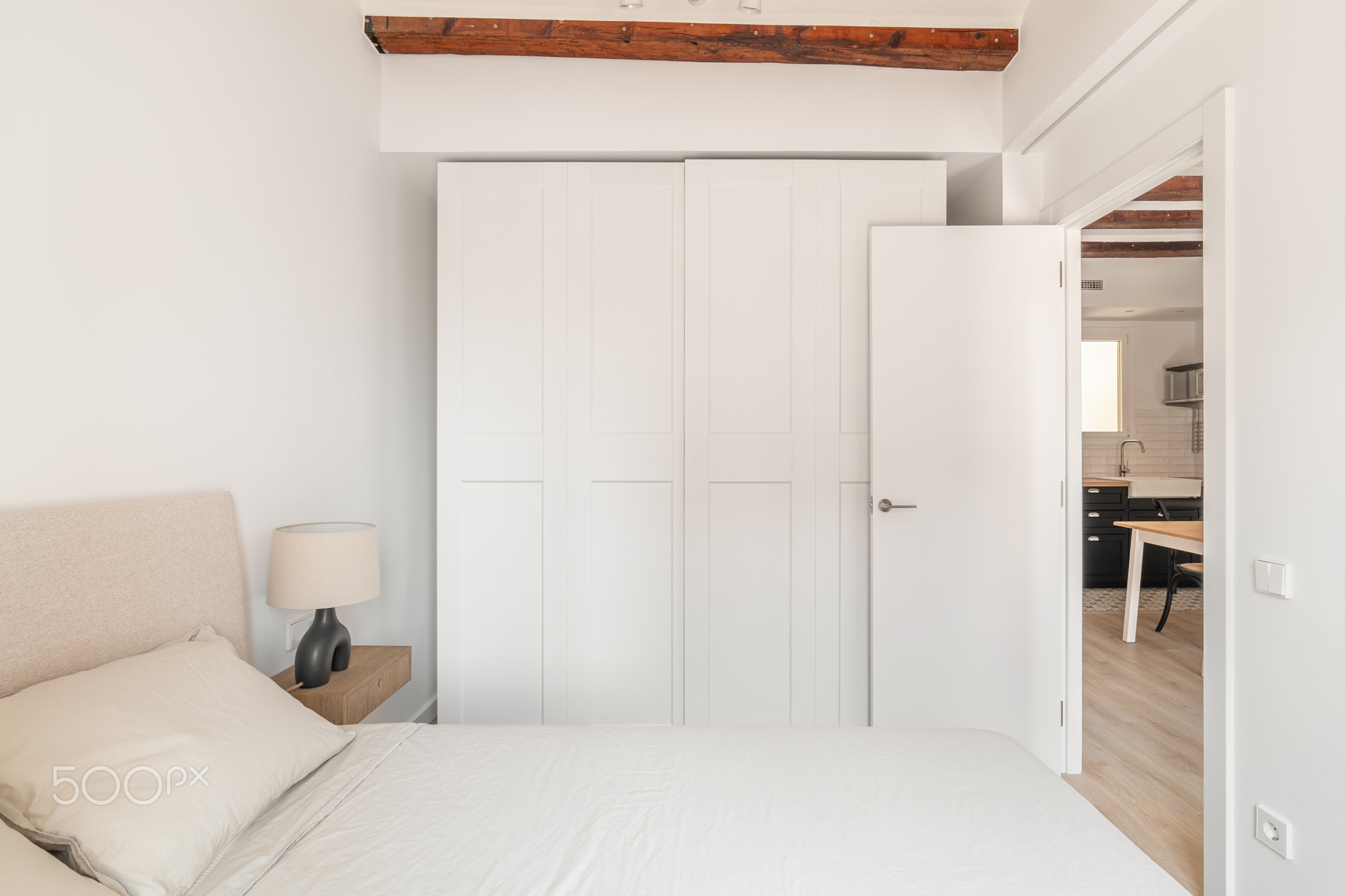 Closet and comfortable double bed in white bedroom