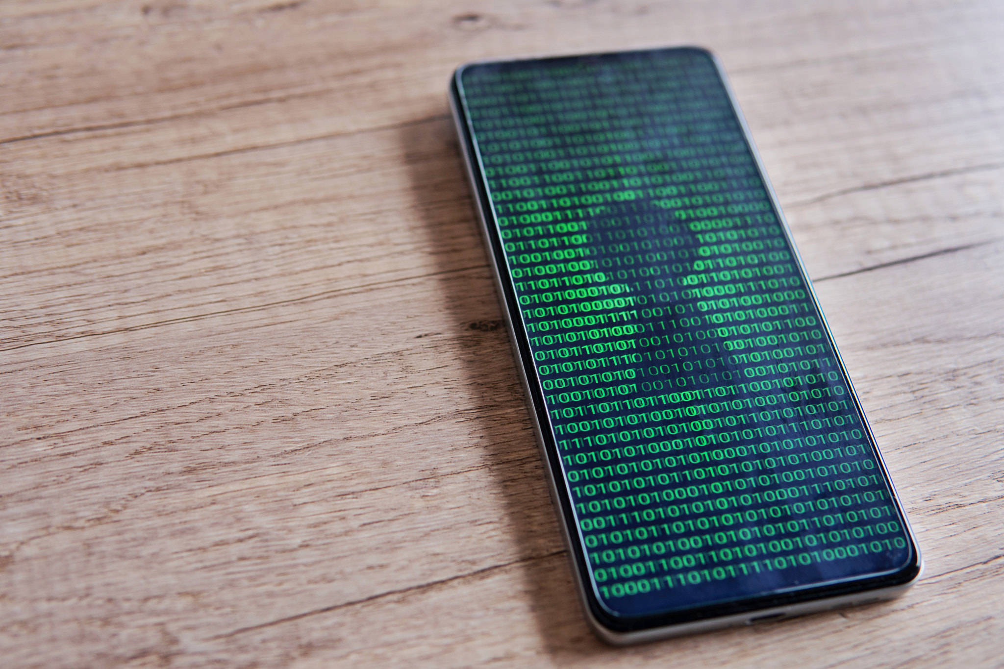 Smartphone with glowing binary code and keyhole on the screen. 