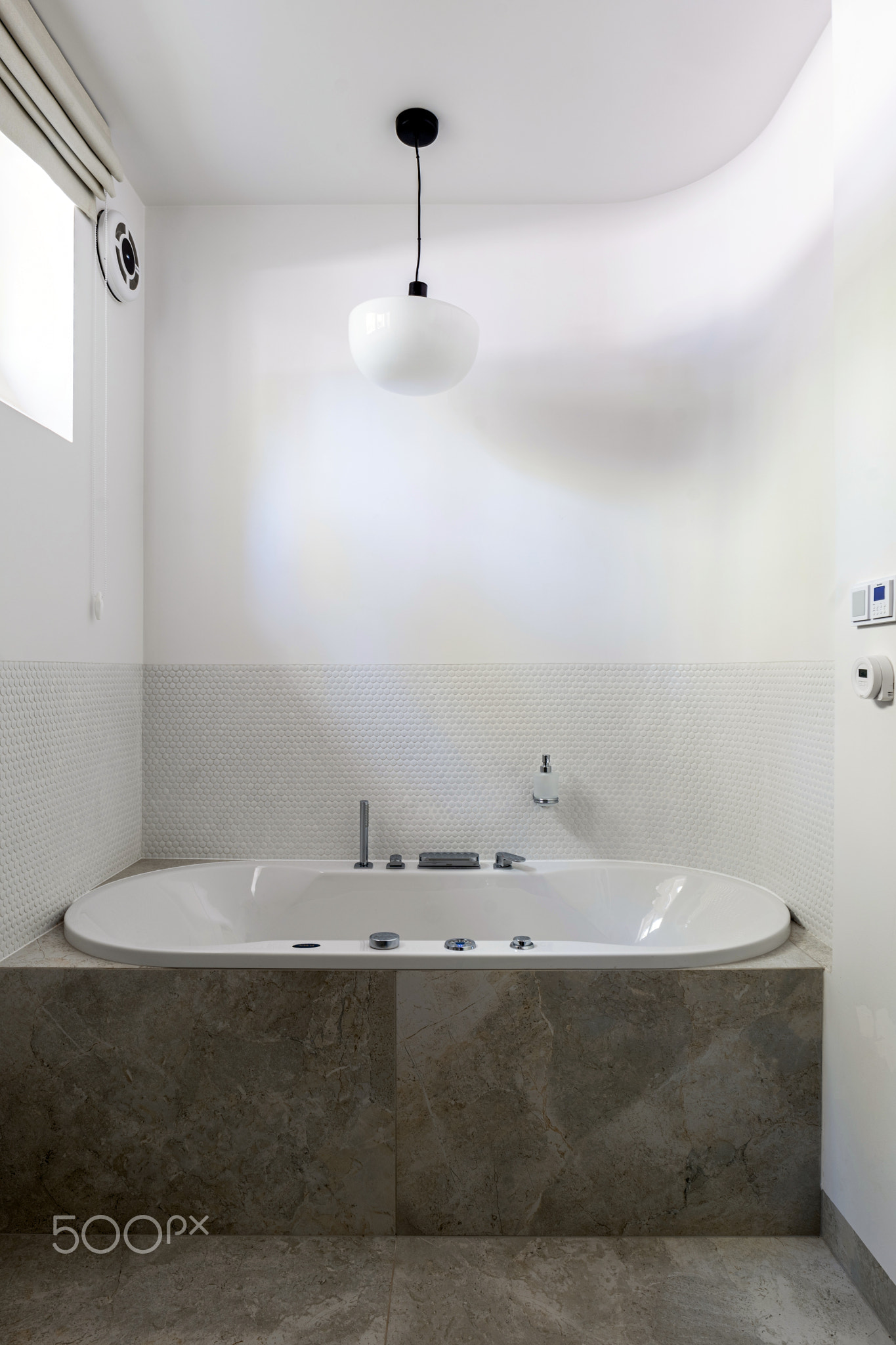 Bathroom with a bathtub and window, featuring plumbing fixture and wood floor