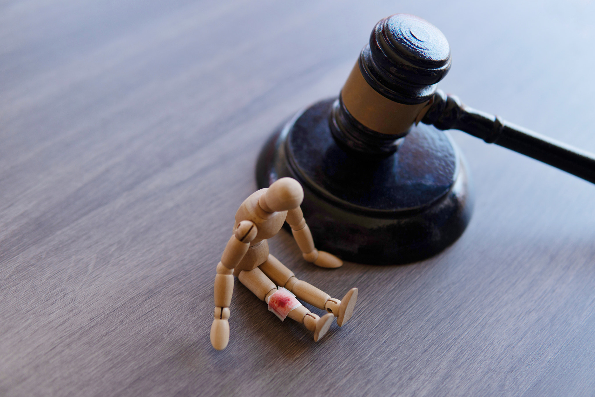 Bandage wrap with blood stain, wooden doll and judge gavel.
