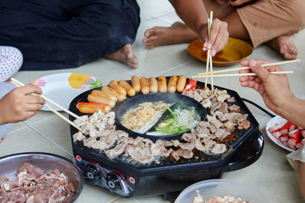 cropped view of people eating meat on electric pan together by Anucha Muphasa on 500px.com