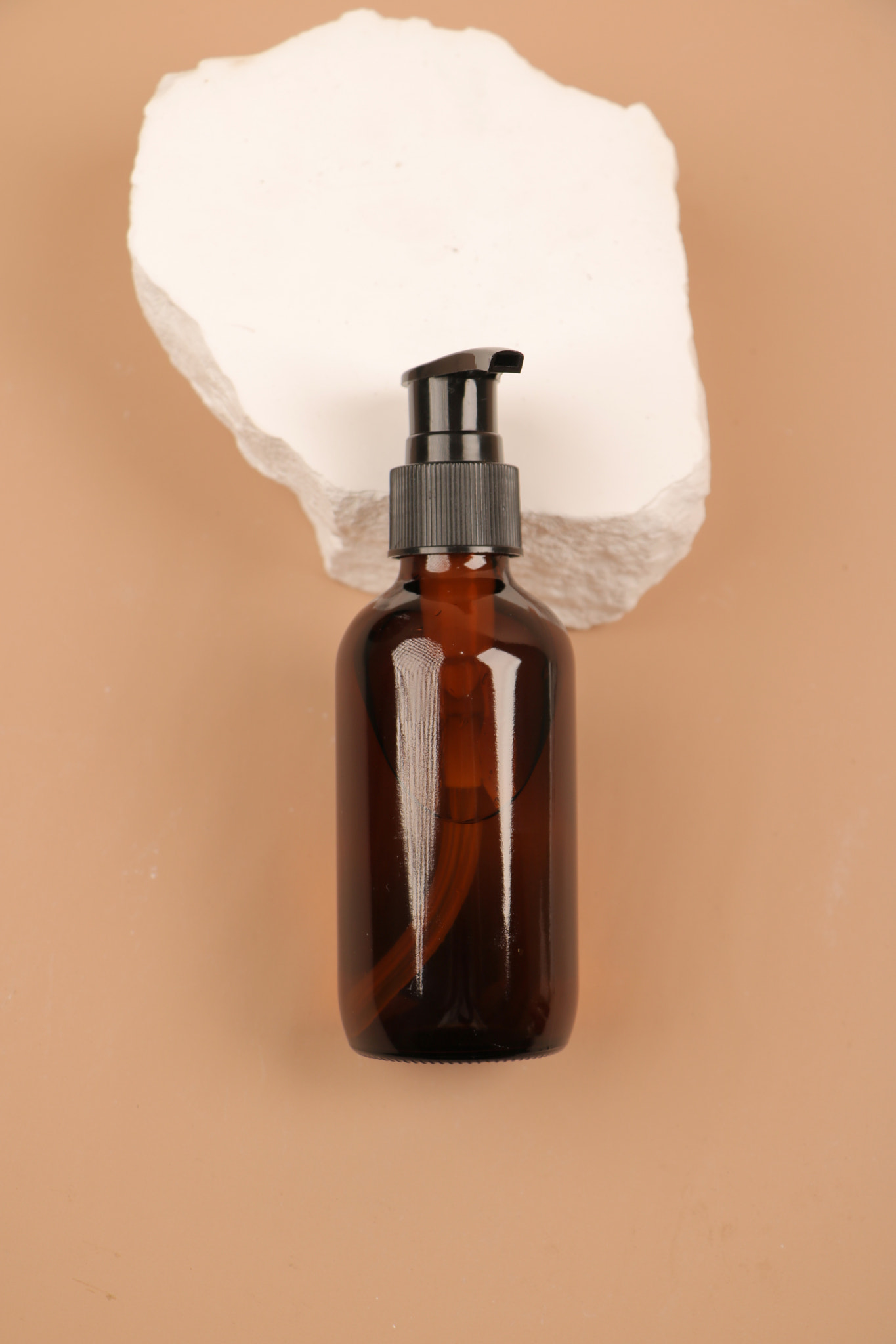 Amber Pump Bottle on Stone Pedestal with Minimalist Background