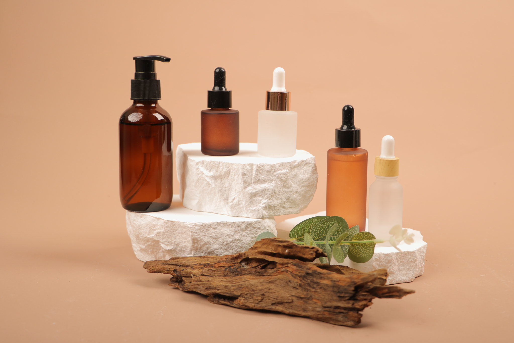 Elegant Assorted Skincare Bottles on Stone Pedestals with Natural Elements