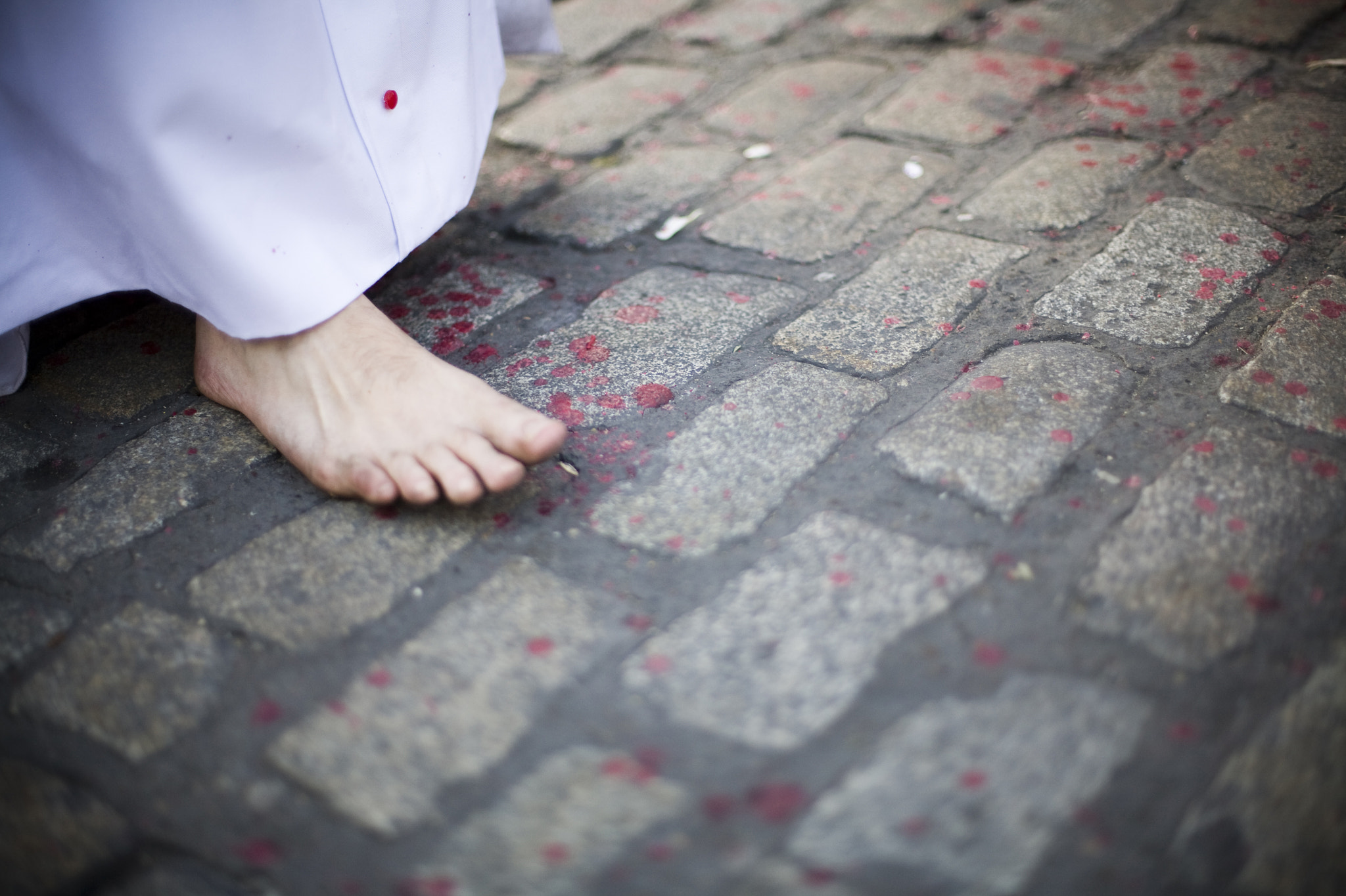 Detail of a barefoot penitent walking on the pavement with melted wax drops, Holy Week 2008, Seville