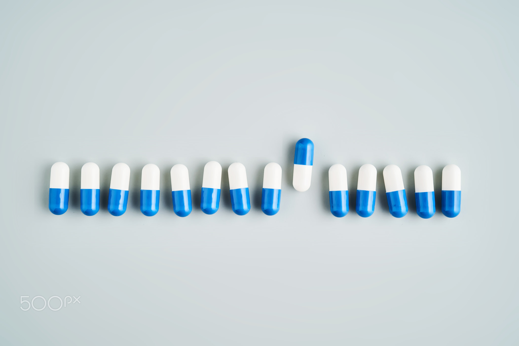 A row of white and blue pills on a blue background.