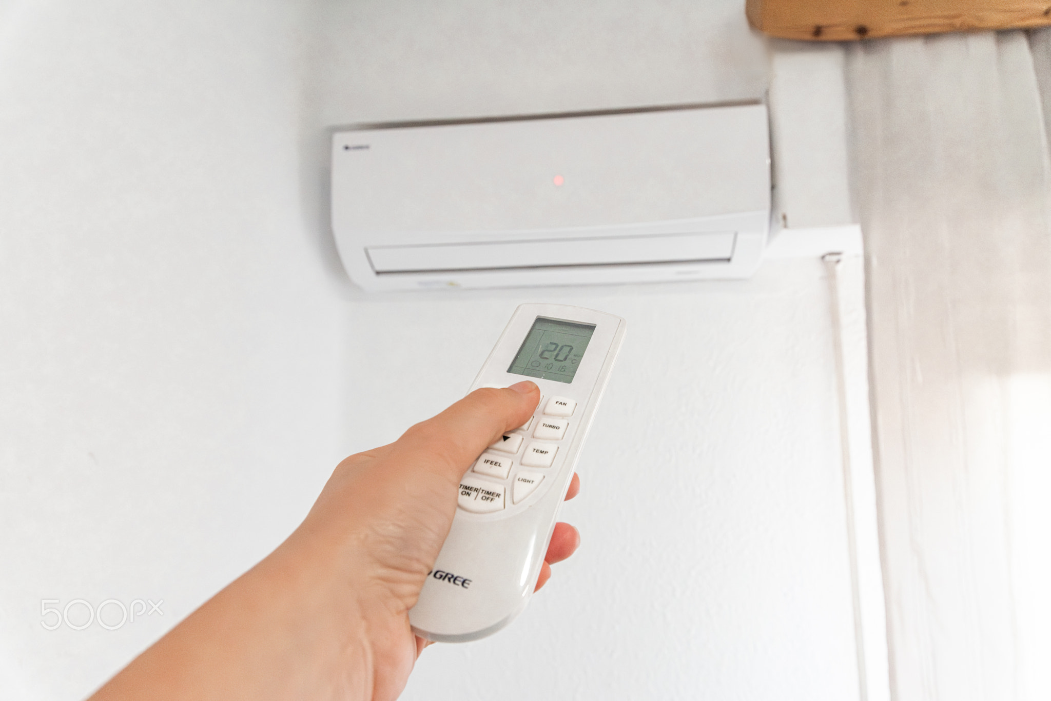 Hand Holding Remote Control Adjusting Air Conditioner