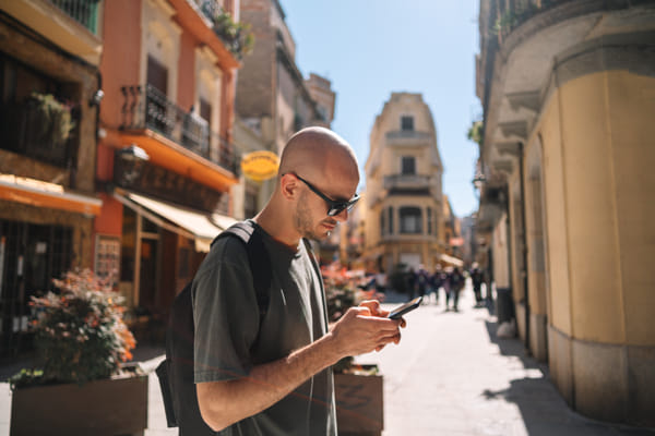 Man using mobile phone while standing by wall by Olha Dobosh on 500px.com