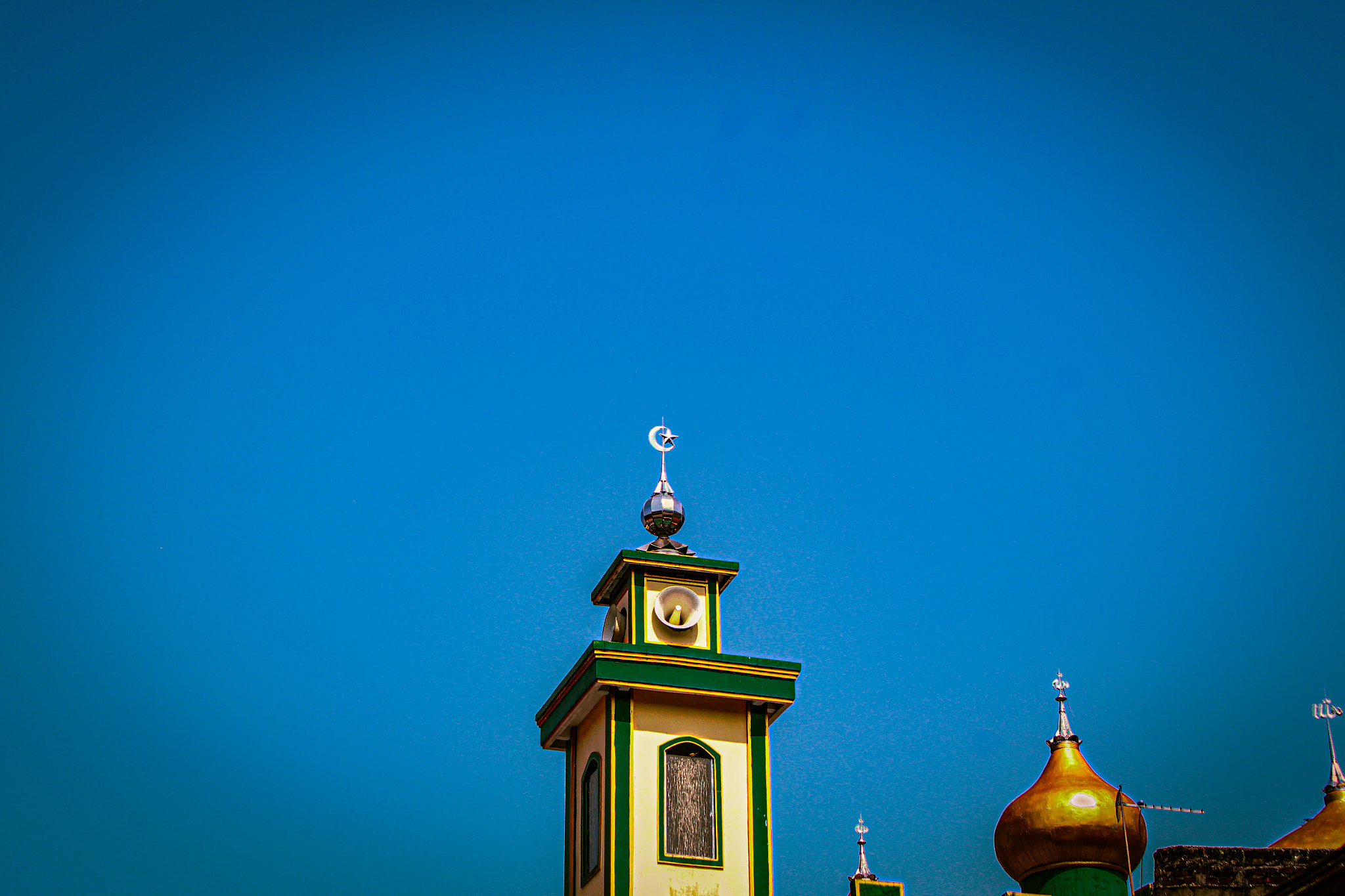 High mosque minaret under blue sky